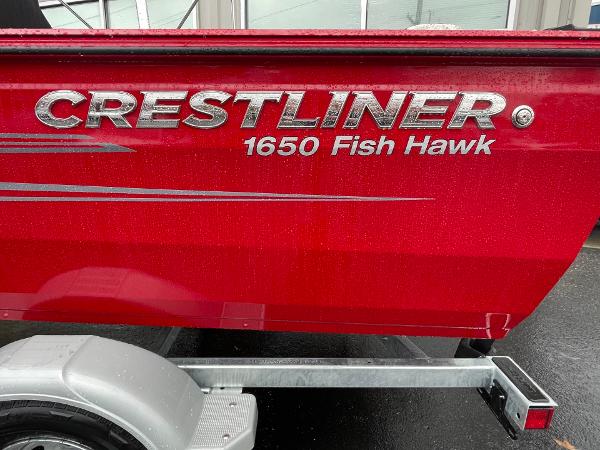 Red 2021 Crestliner 1650 Fish Hawk SC boat on trailer, side view.