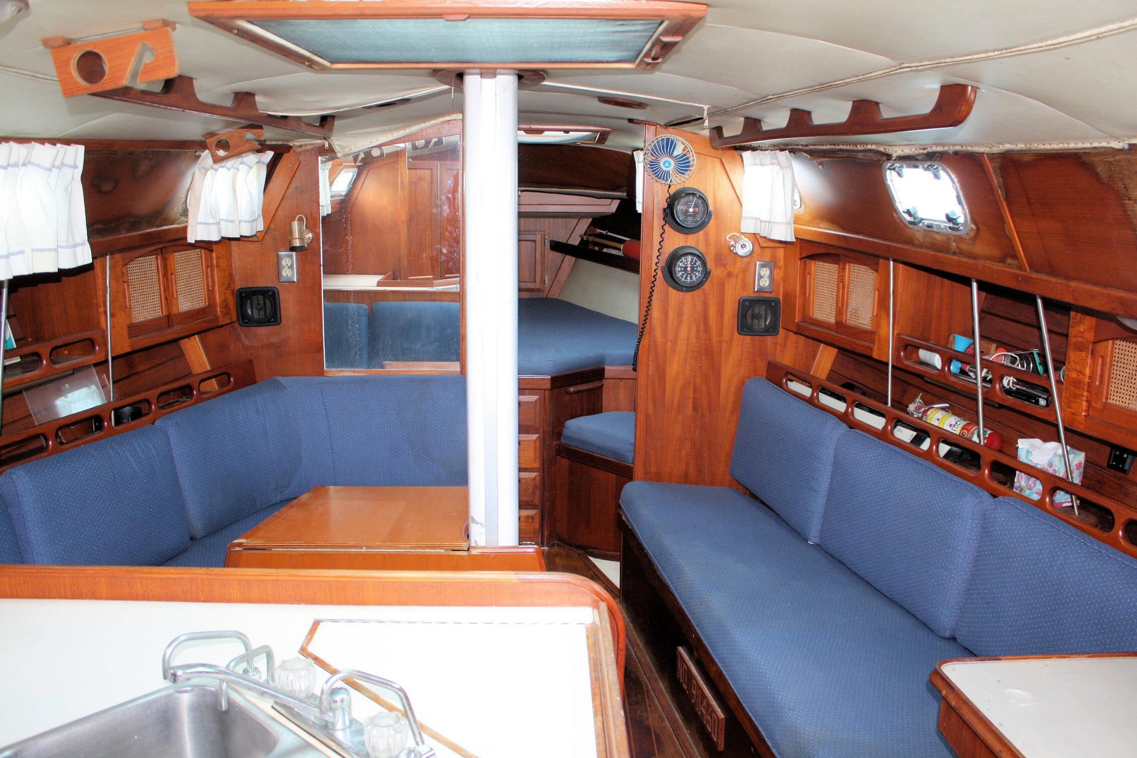 Interior of a 1987 Ericson 38-200 sailboat with blue seating and wooden accents.