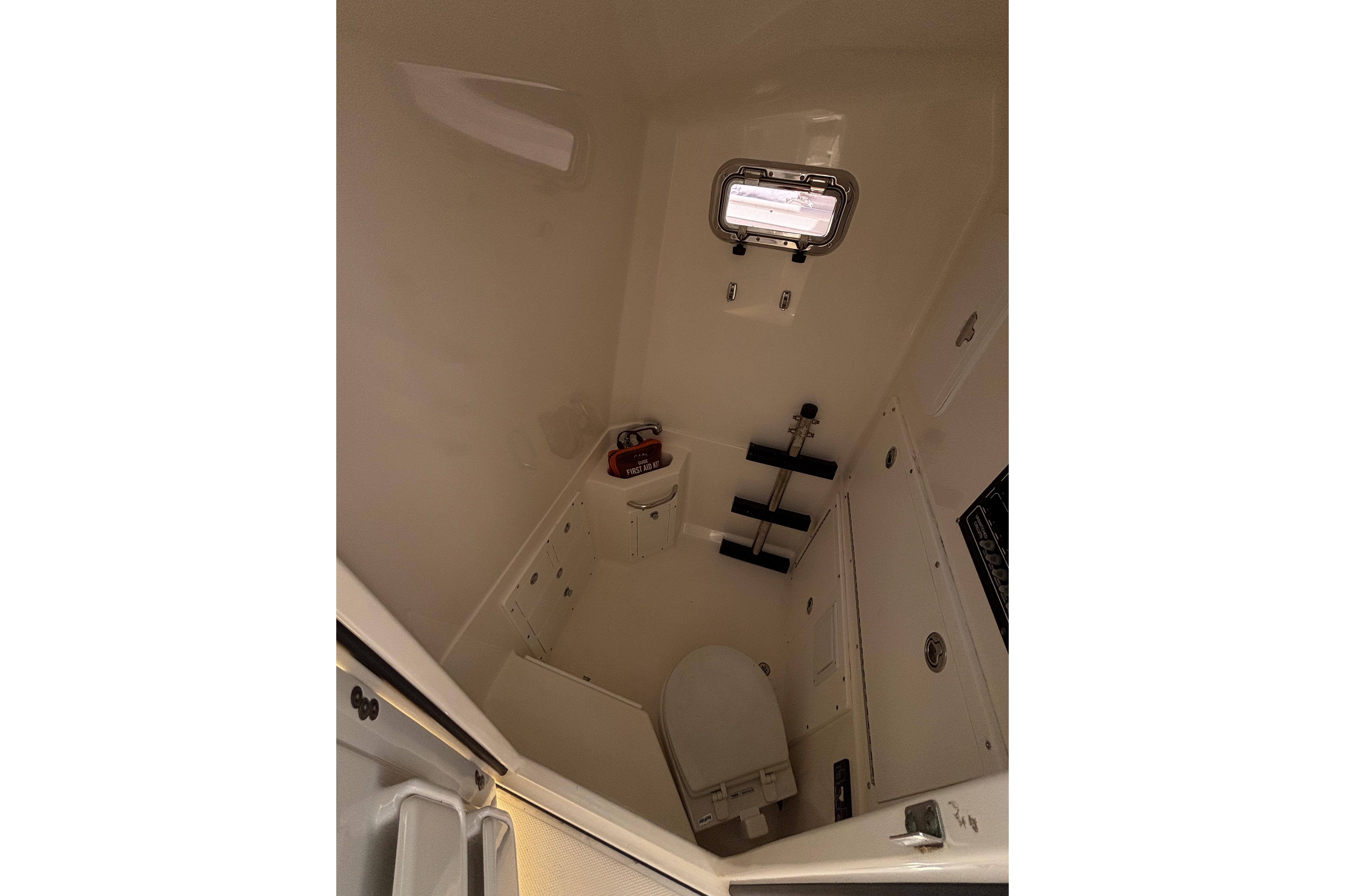 Interior of a 2006 Edgewater 318CC boat's compact bathroom with toilet and window.