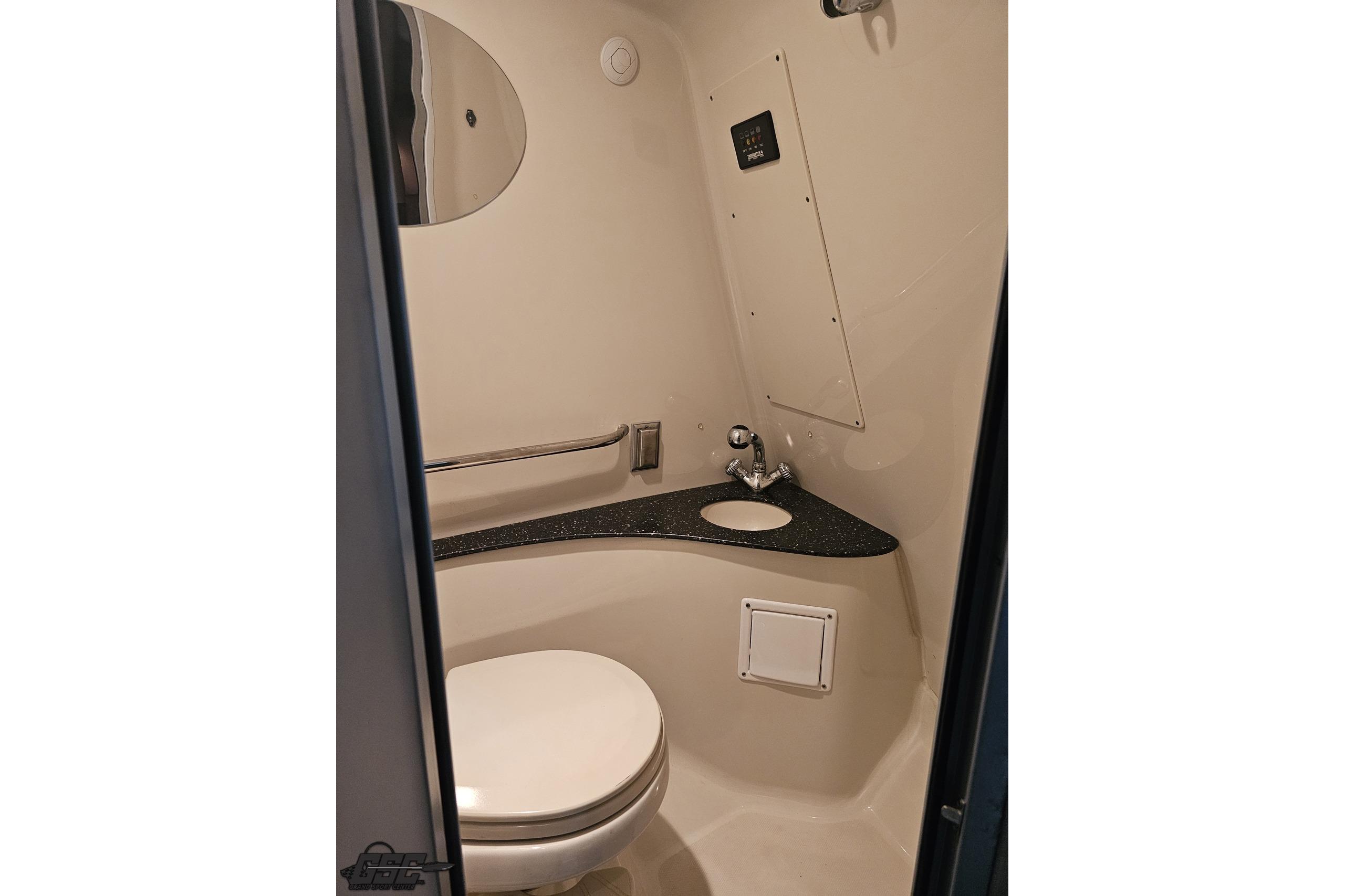 Compact bathroom in a 2008 Baja 335 Performance boat, featuring a toilet and sink.