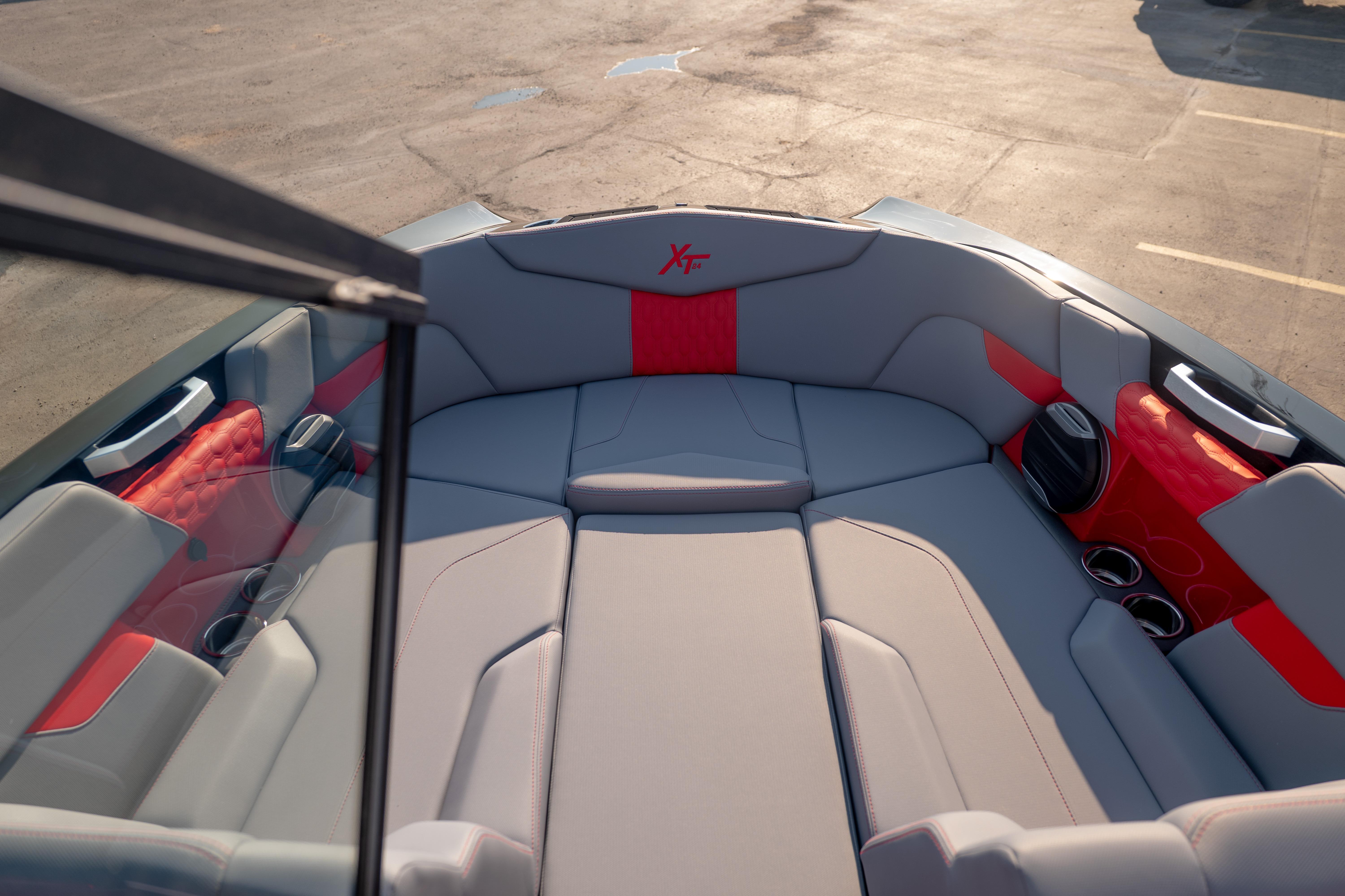 Interior of 2027 MasterCraft XT24 boat with gray and red seating, cup holders, and speaker.