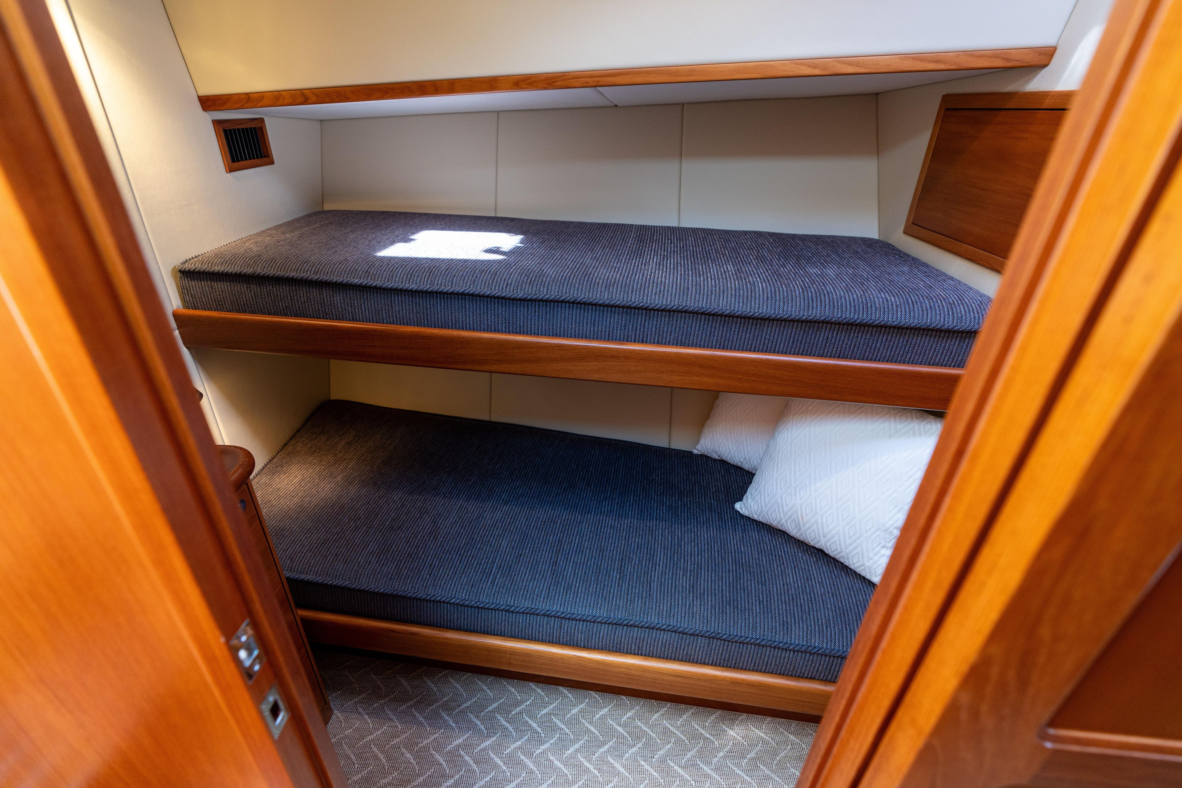 2016 Palm Beach Motor Yachts PB50 cabin with wooden bunk beds and blue cushions.