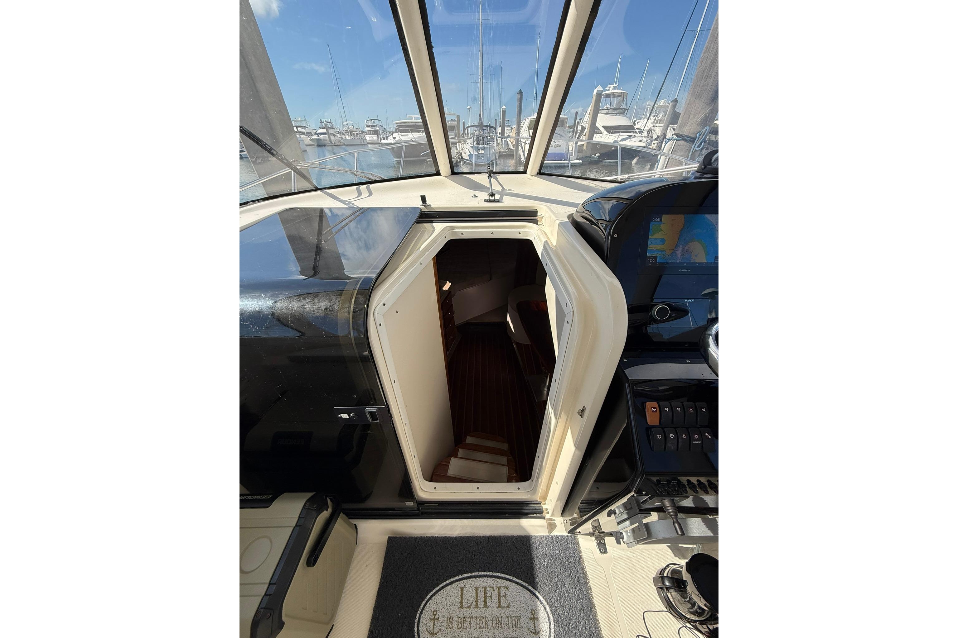 2004 Pursuit 3370 Offshore boat interior with open cabin door, marina view.