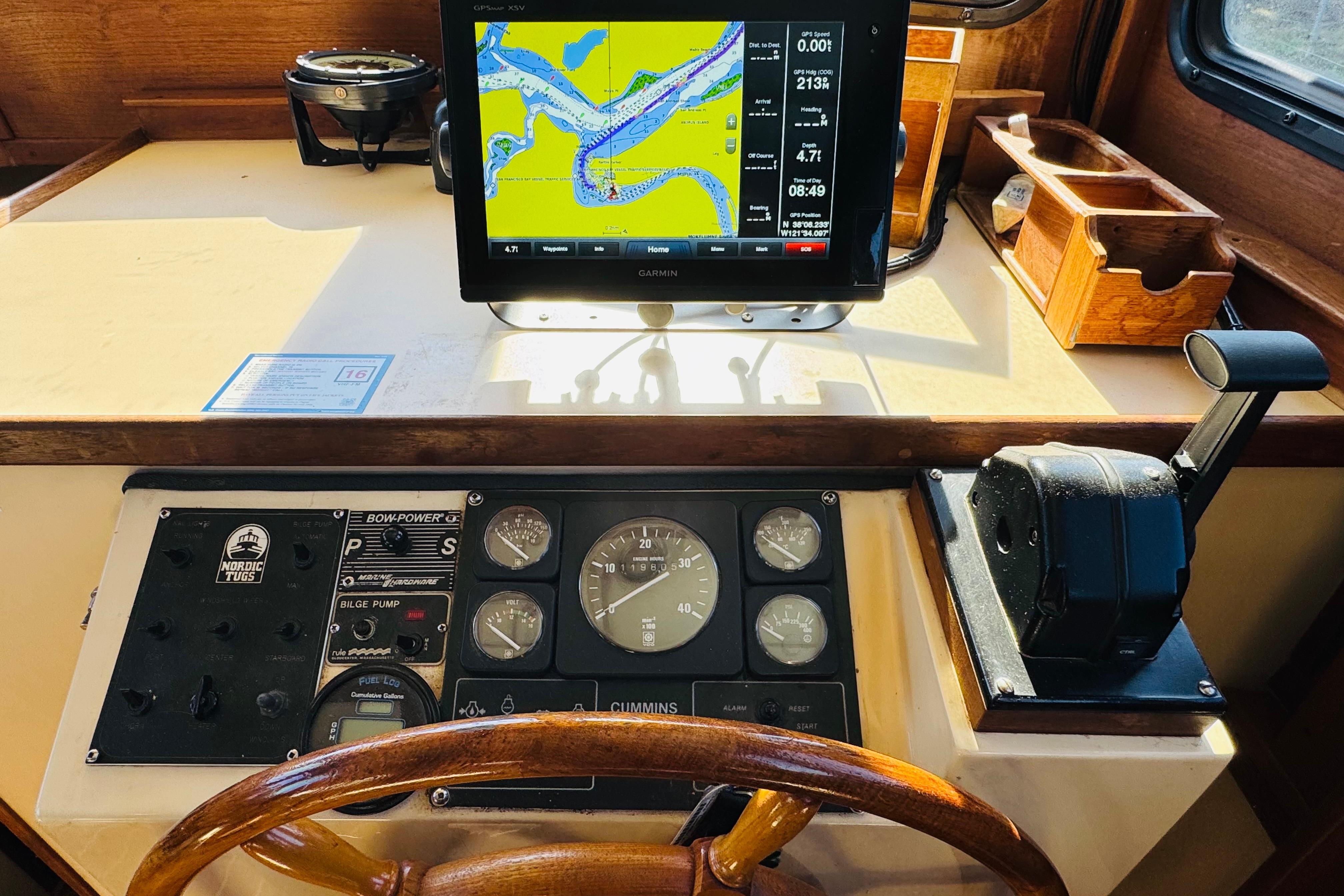 1996 Nordic Tug 32 helm with navigation display, gauges, and wooden steering wheel.