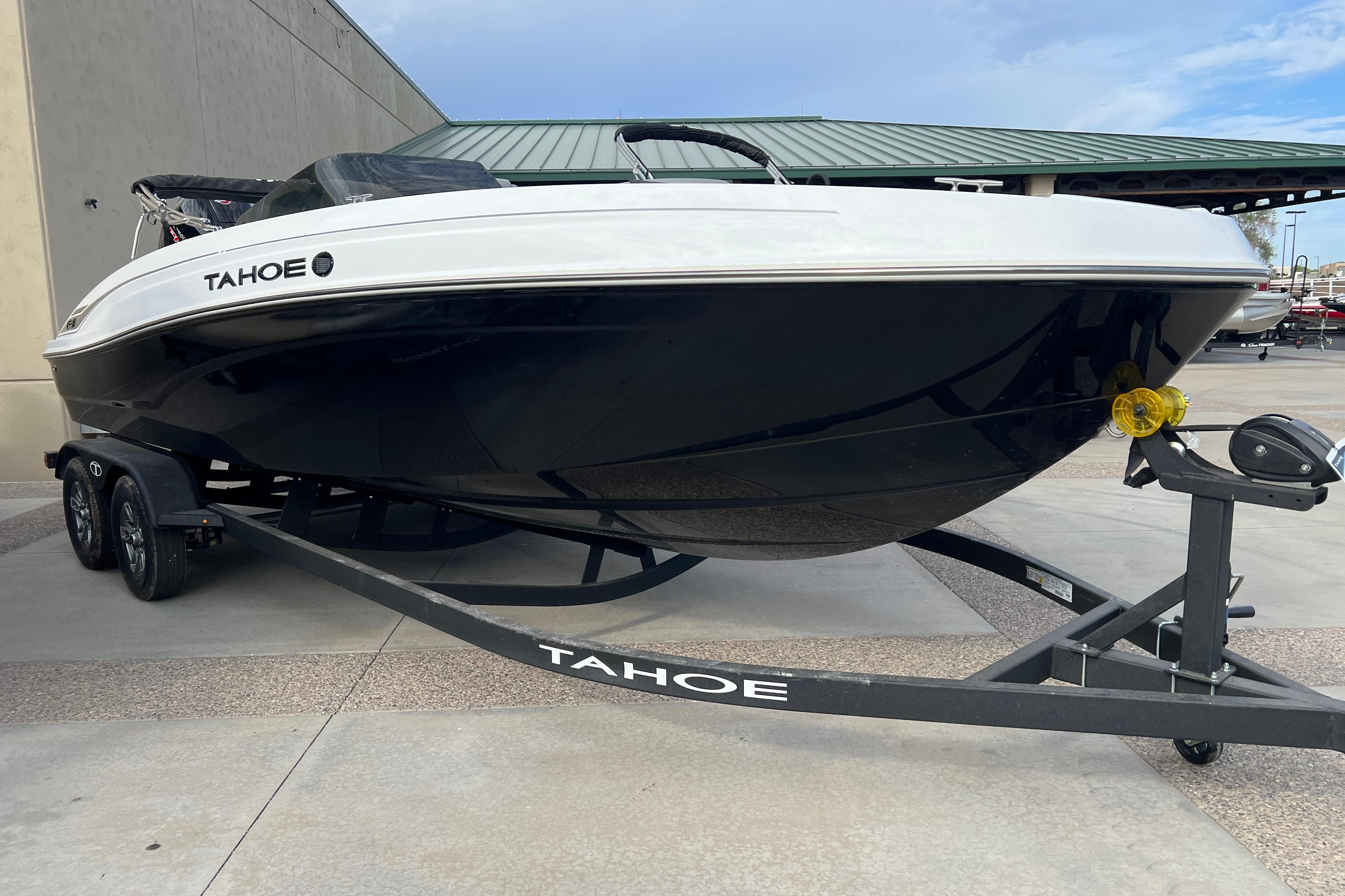 2026 Tahoe T21 boat on trailer, sleek black and white design, parked outdoors.