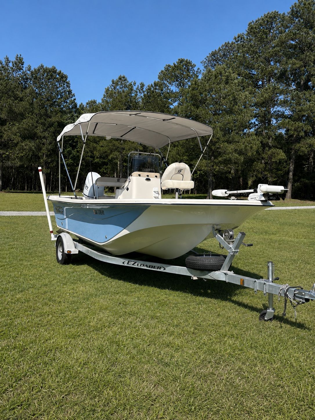 A 2022 Carolina Skiff 17 LS boat on a trailer, set on a grassy field.