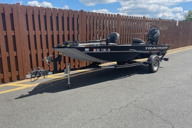 2019 Tracker Panfish 16 boat on trailer, parked by wooden fence under blue sky.