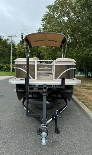 2025 Sun Tracker SportFish 22 XP3 pontoon boat on trailer, parked on a road.