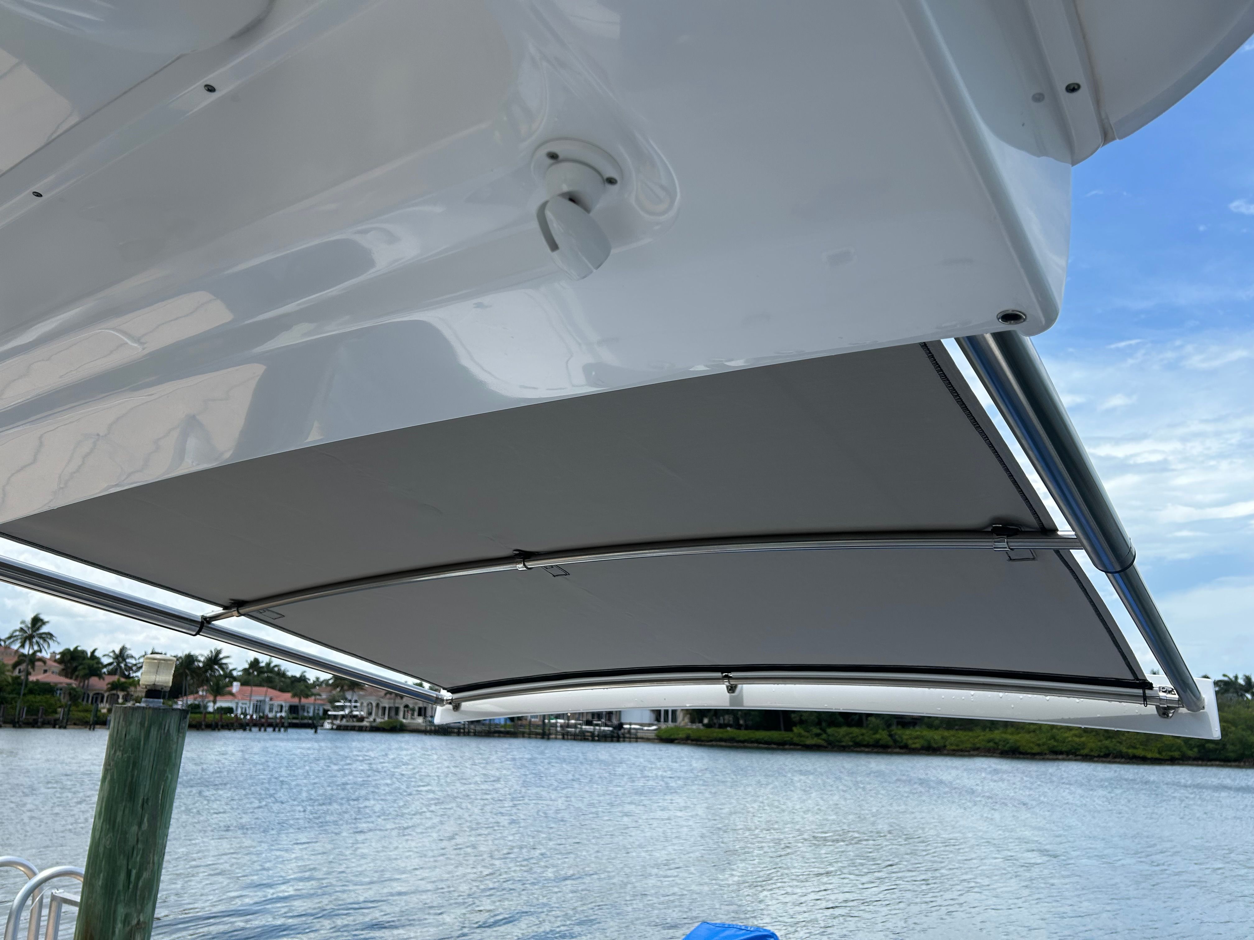 Intrepid 375 Nomad SE 2025 with retractable sunshade by the water.