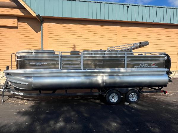 2025 Sun Tracker SportFish 22 DLX pontoon boat on trailer, parked outdoors.