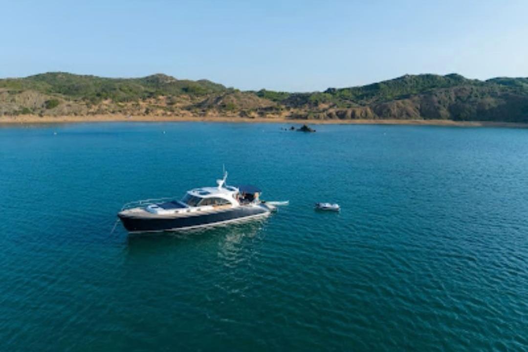 2009 Franchini Emozione yacht anchored in serene blue waters near a rocky coastline.
