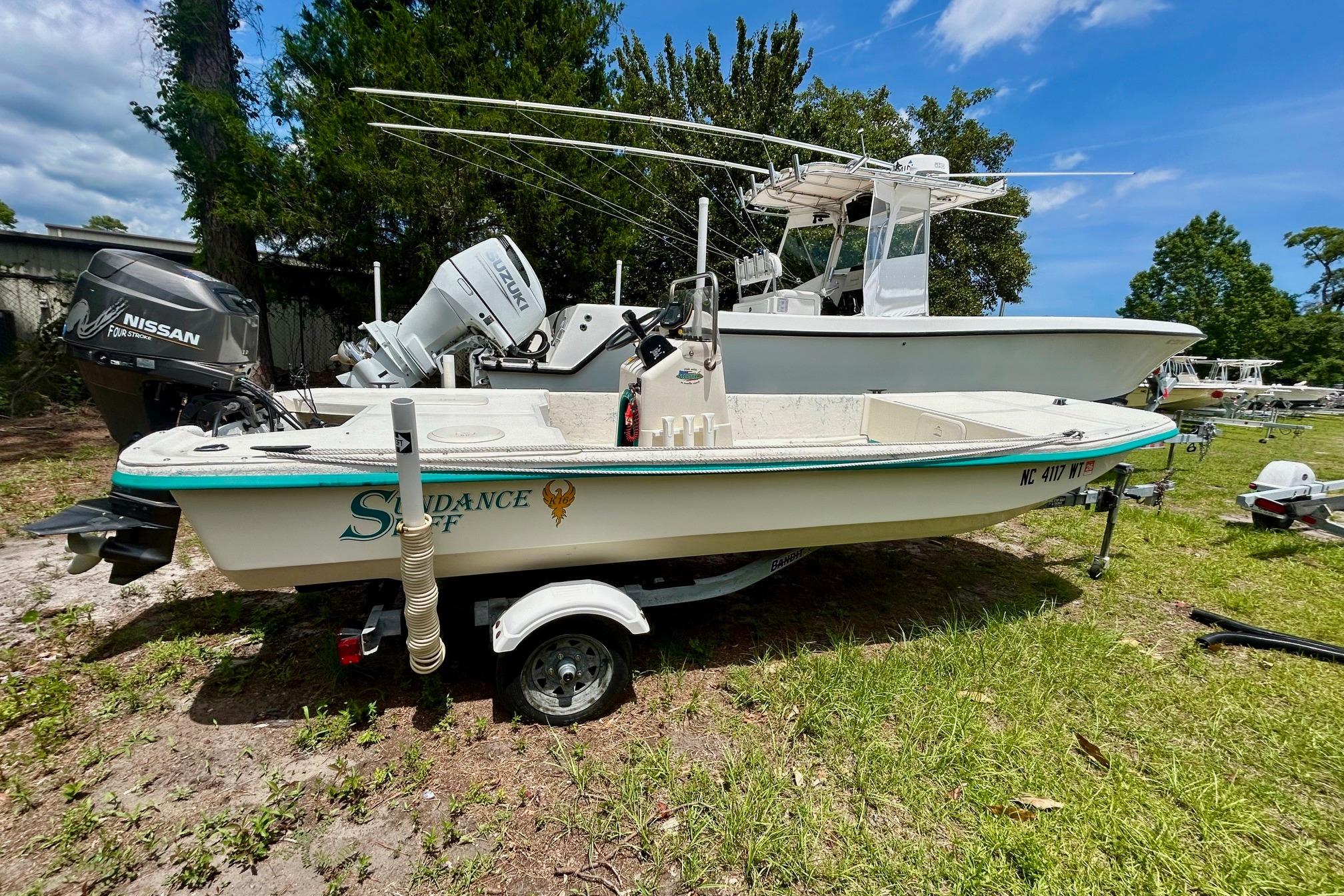 2002 Sundance K16CC boat with Nissan outboard motor on grassy area.