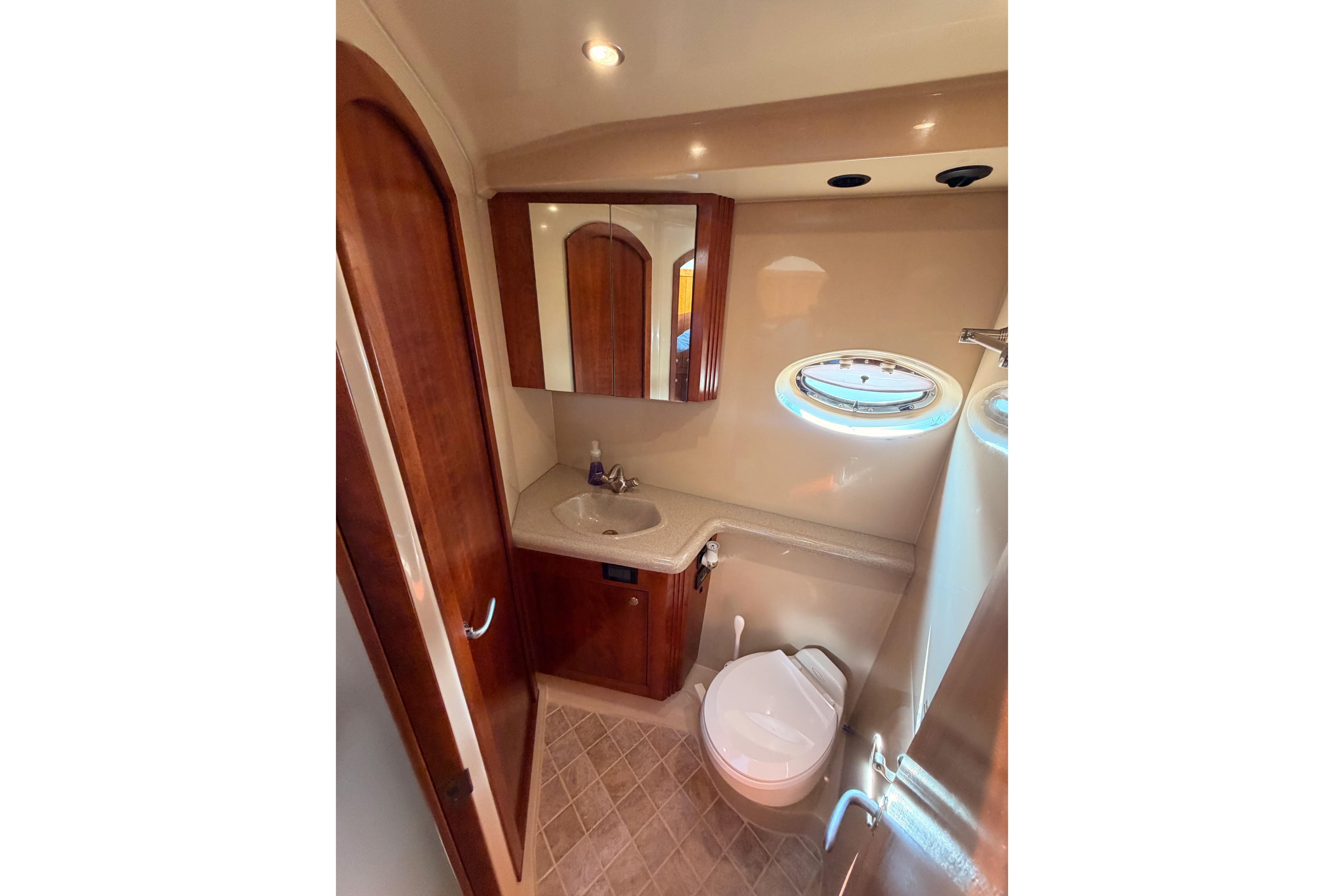 Luxurious bathroom in 2005 Cruisers Yachts 405 Express Motoryacht with wood accents and porthole.