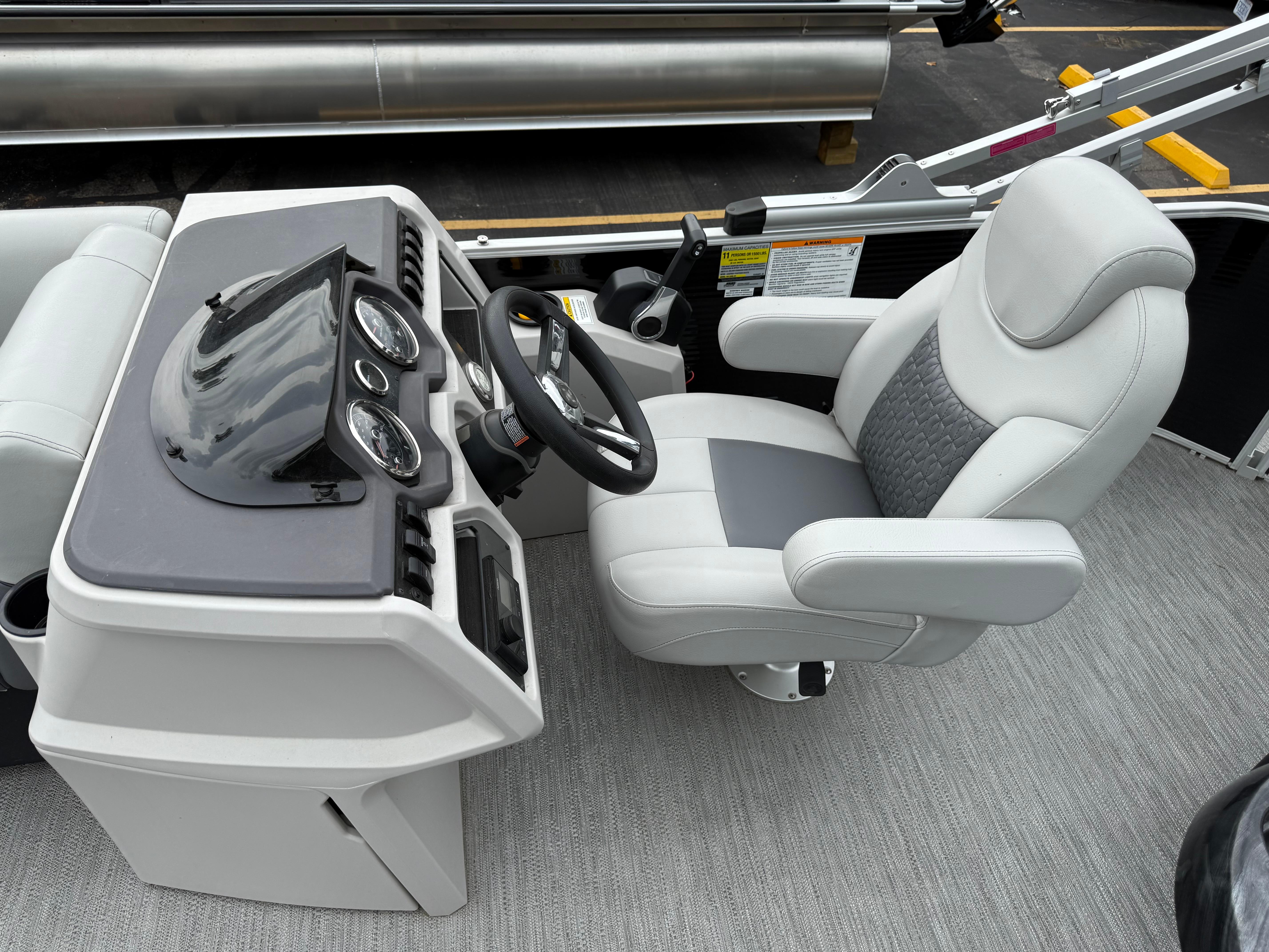 Captain's seat and dashboard of 2023 Godfrey Sweetwater boat, featuring modern controls and gauges.