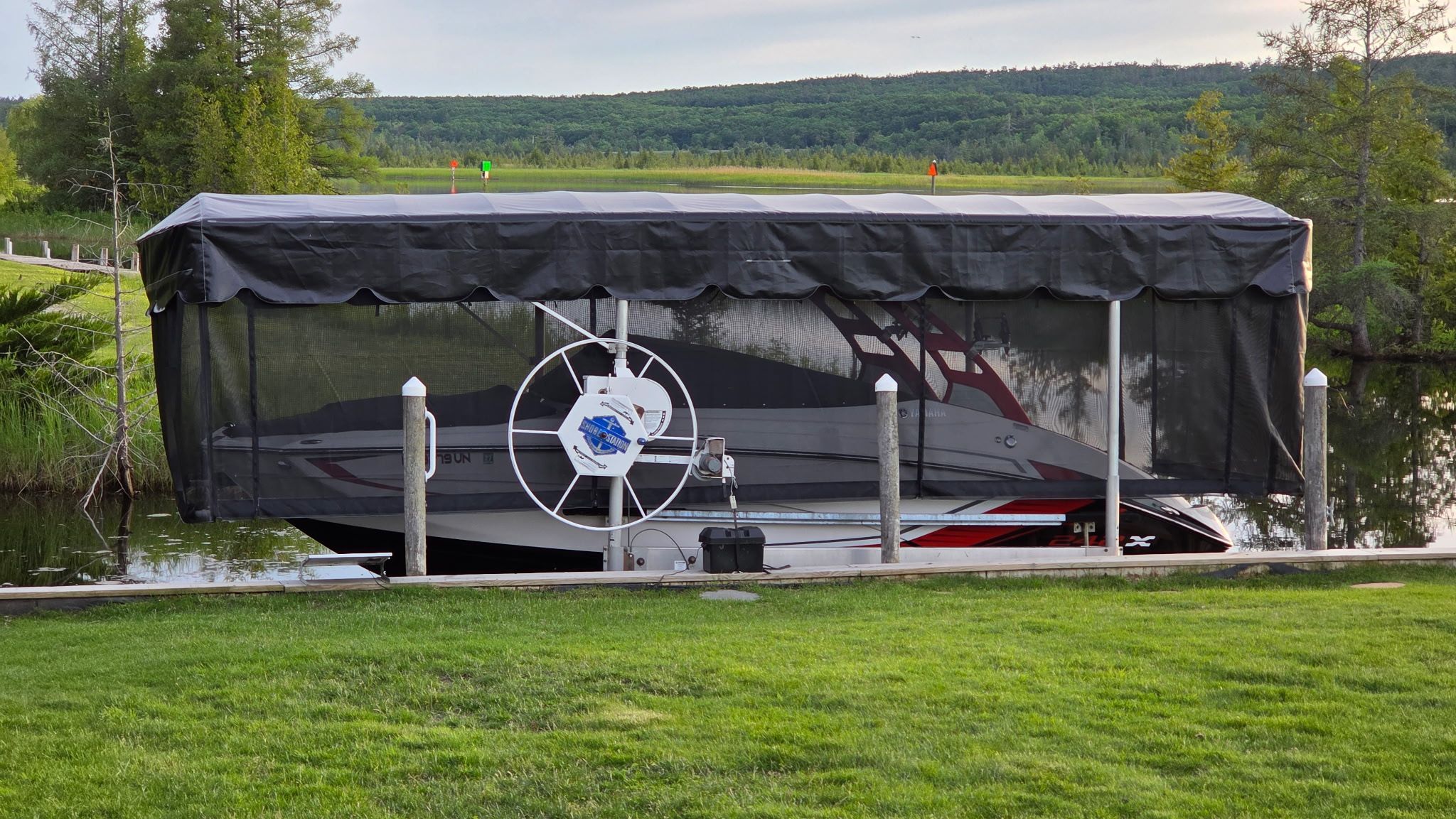 2018 Yamaha 242X E-Series under a covered boat lift by a calm river.