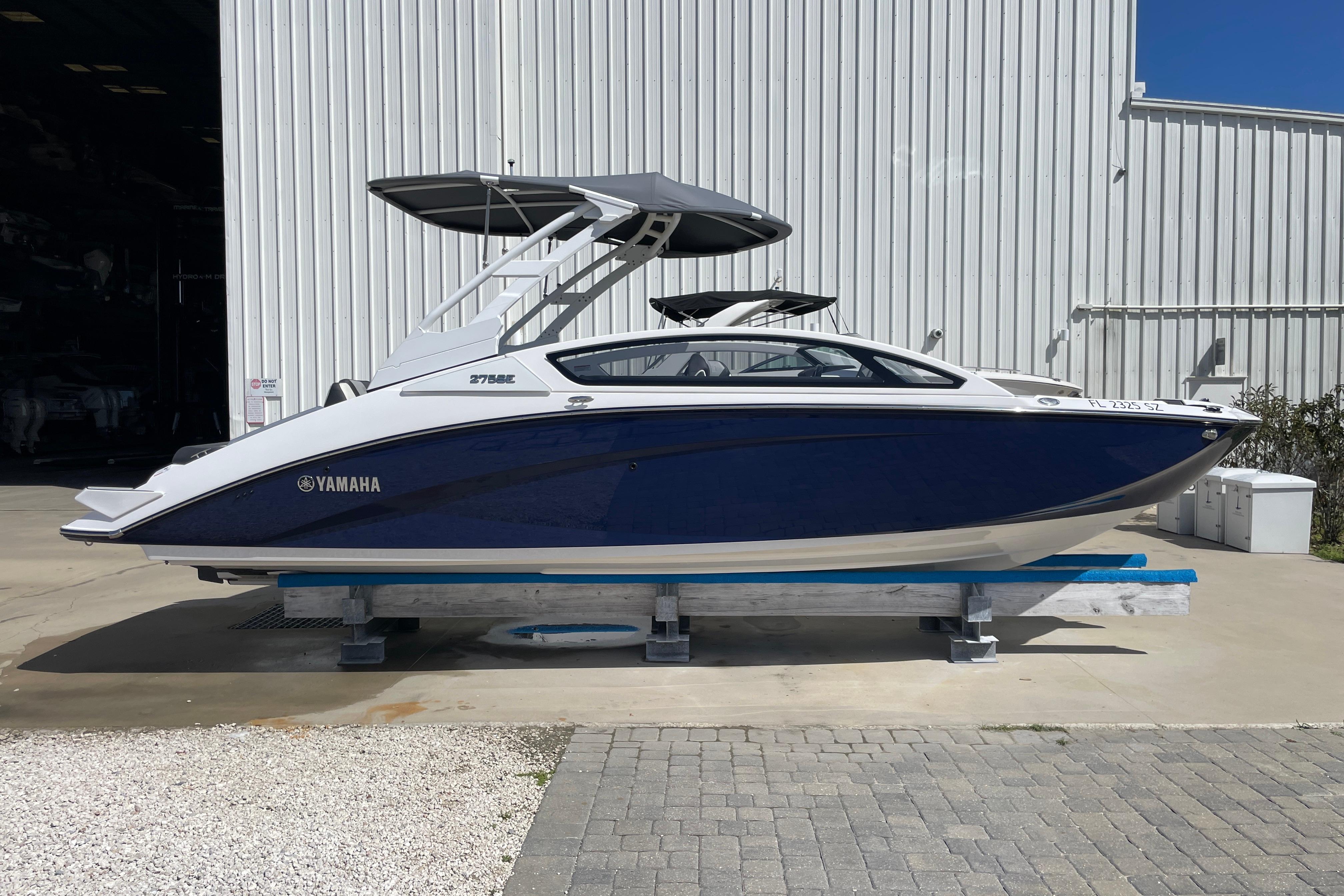 2021 Yamaha Boats 275SE in blue and white, displayed outdoors on a stand.