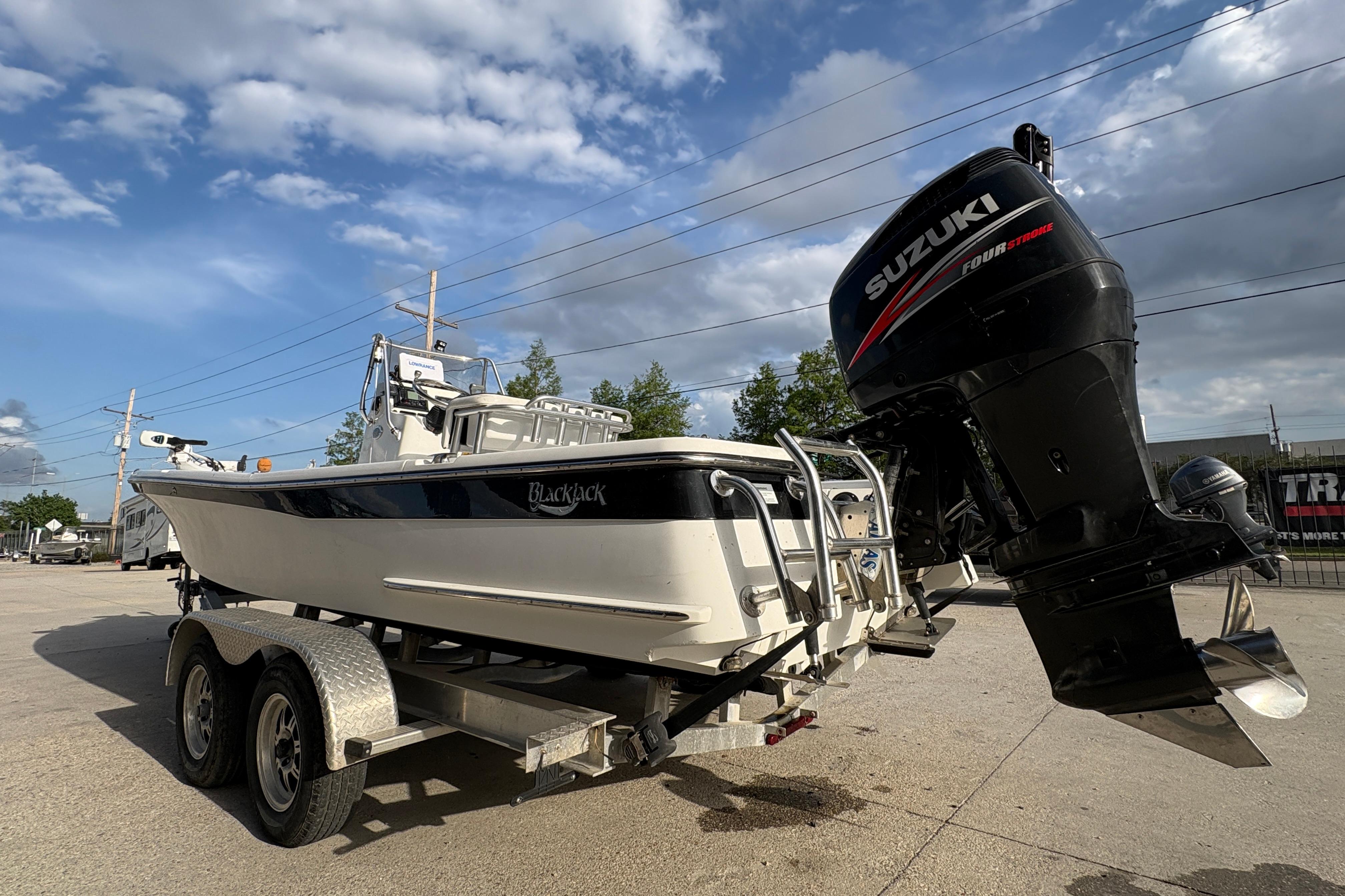 2012 BlackJack 224 boat with Suzuki outboard motor on a trailer under a cloudy sky.