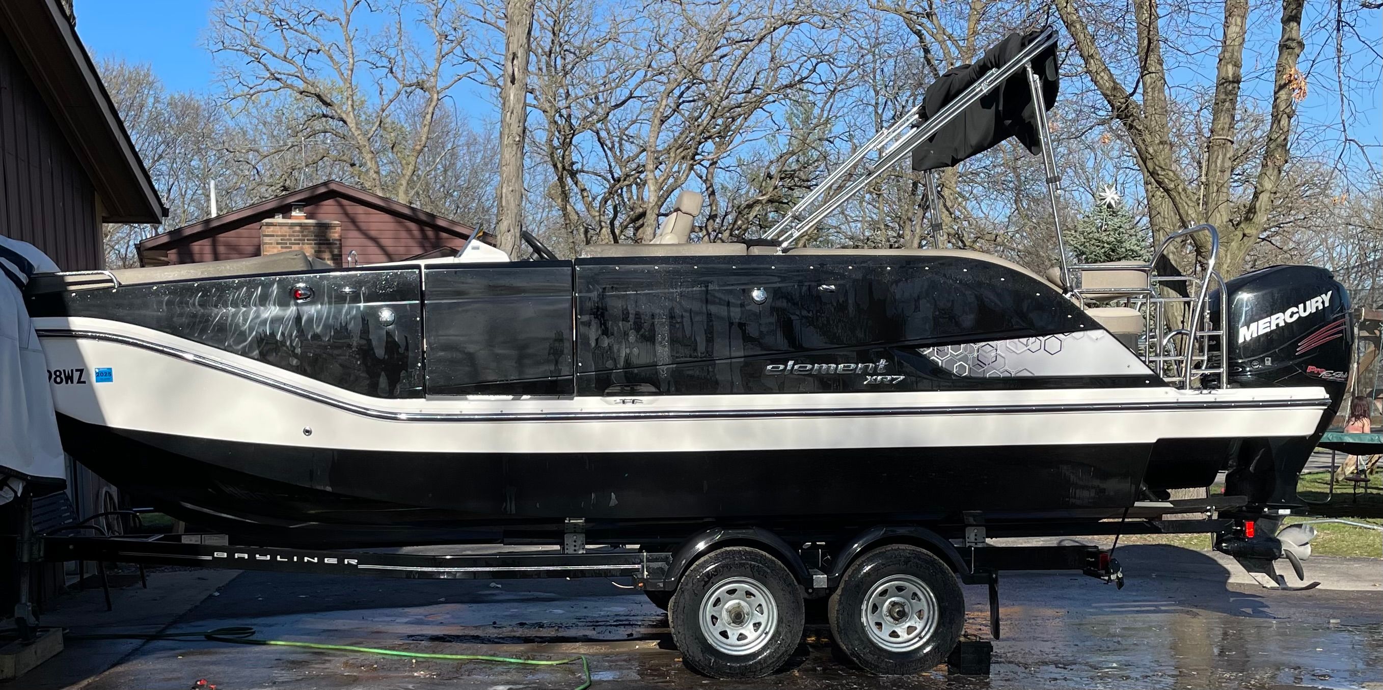 A 2016 Bayliner Element XR7 on a trailer in a yard.