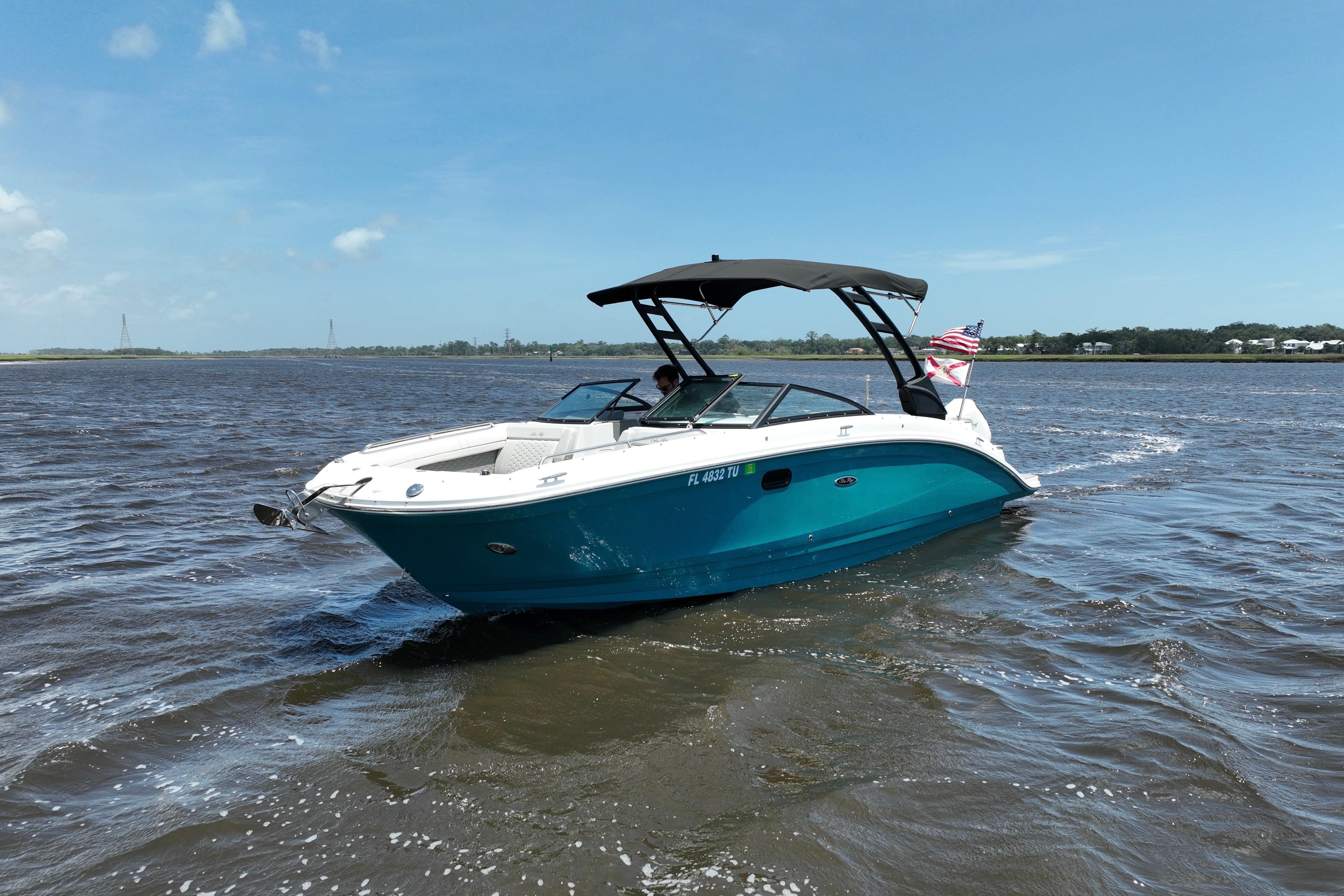 2024 Sea Ray SDX 270 Outboard boat cruising on a sunny day with an American flag.