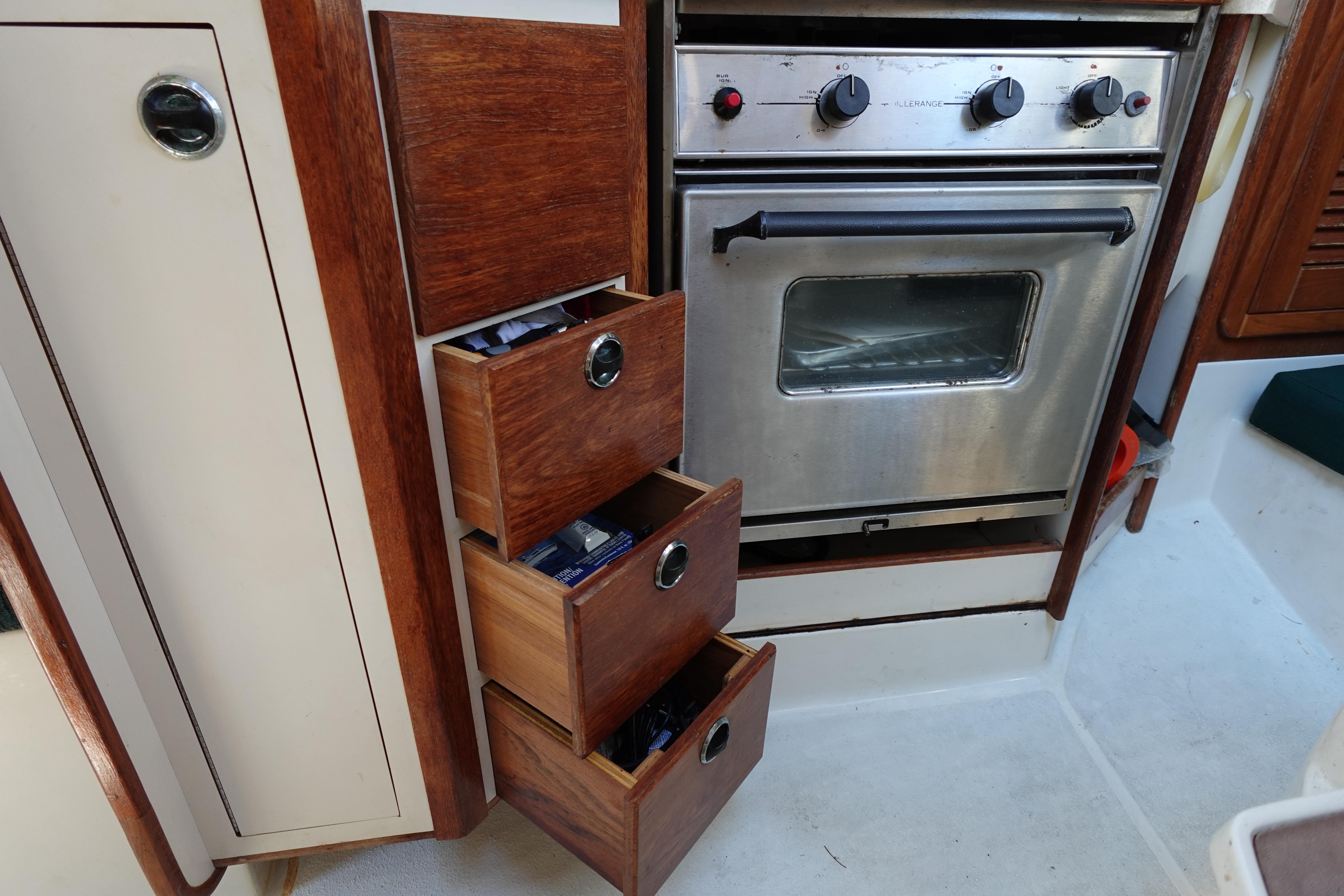 Interior of 1997 Catalina 28 sailboat with wooden drawers and stainless steel oven.