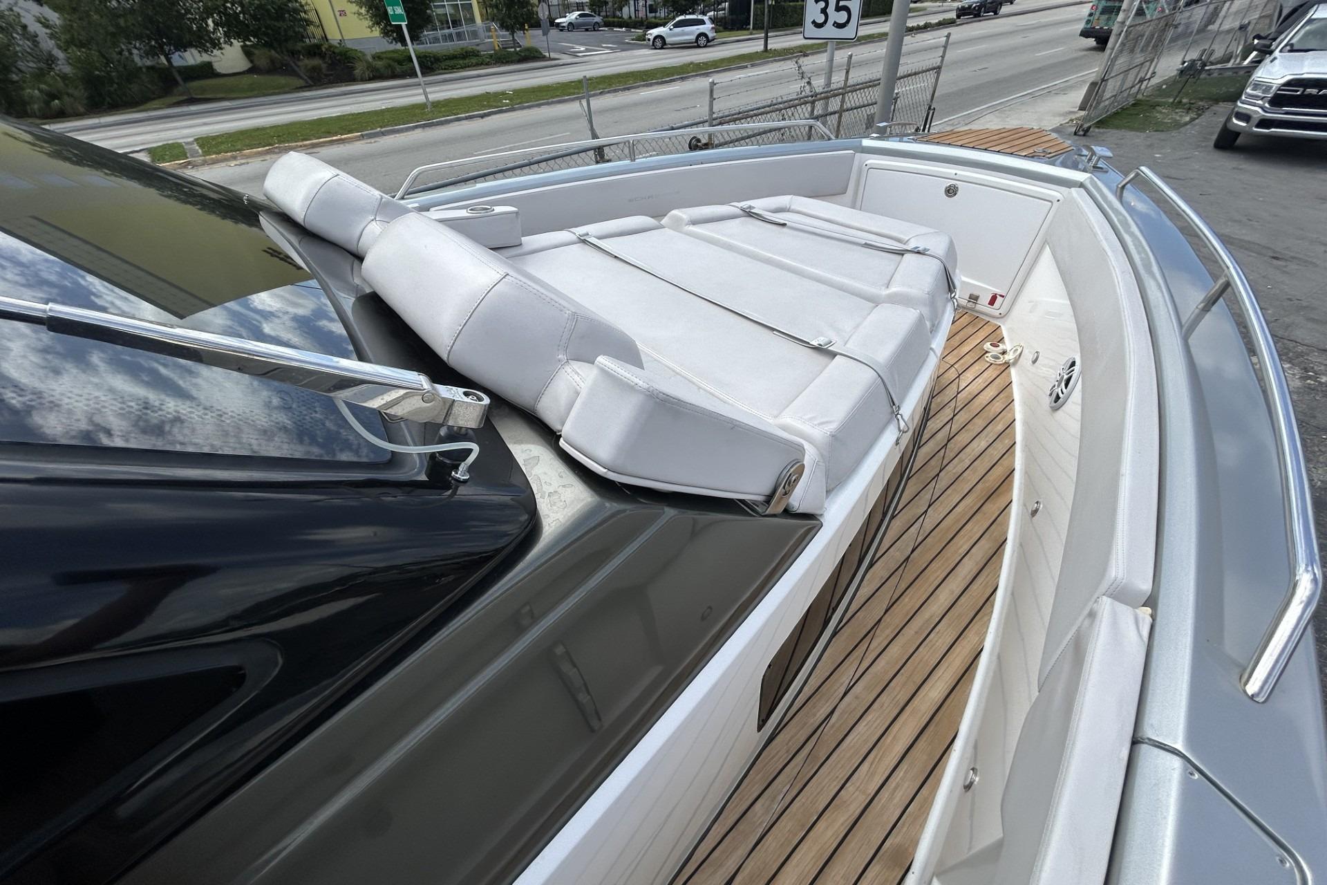 2023 Schaefer V33 yacht with white seating and wooden deck, docked near a road.