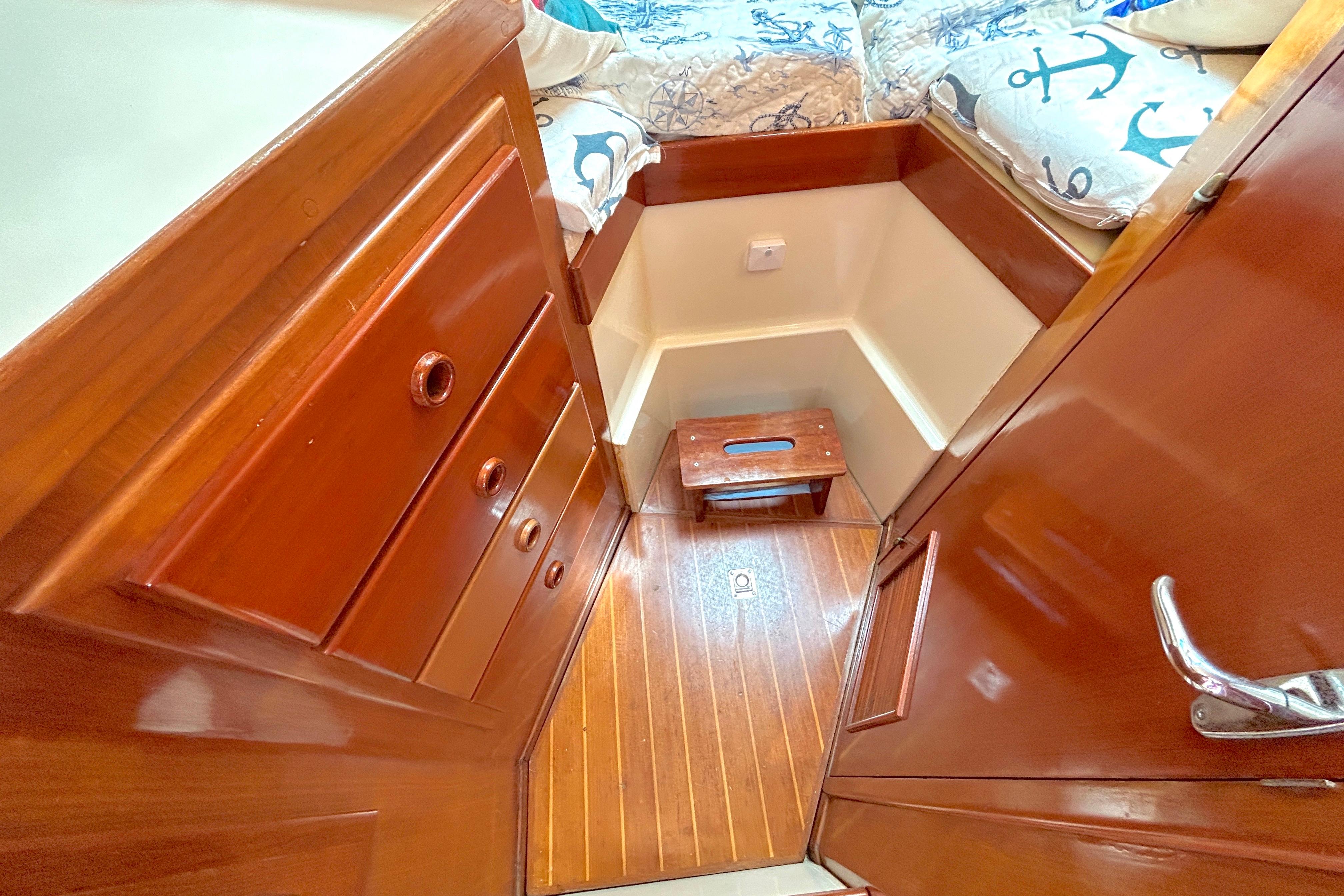 Interior of 1987 Transpacific Marine Eagle 32 Trawler with wooden cabinetry and nautical-themed bedding.