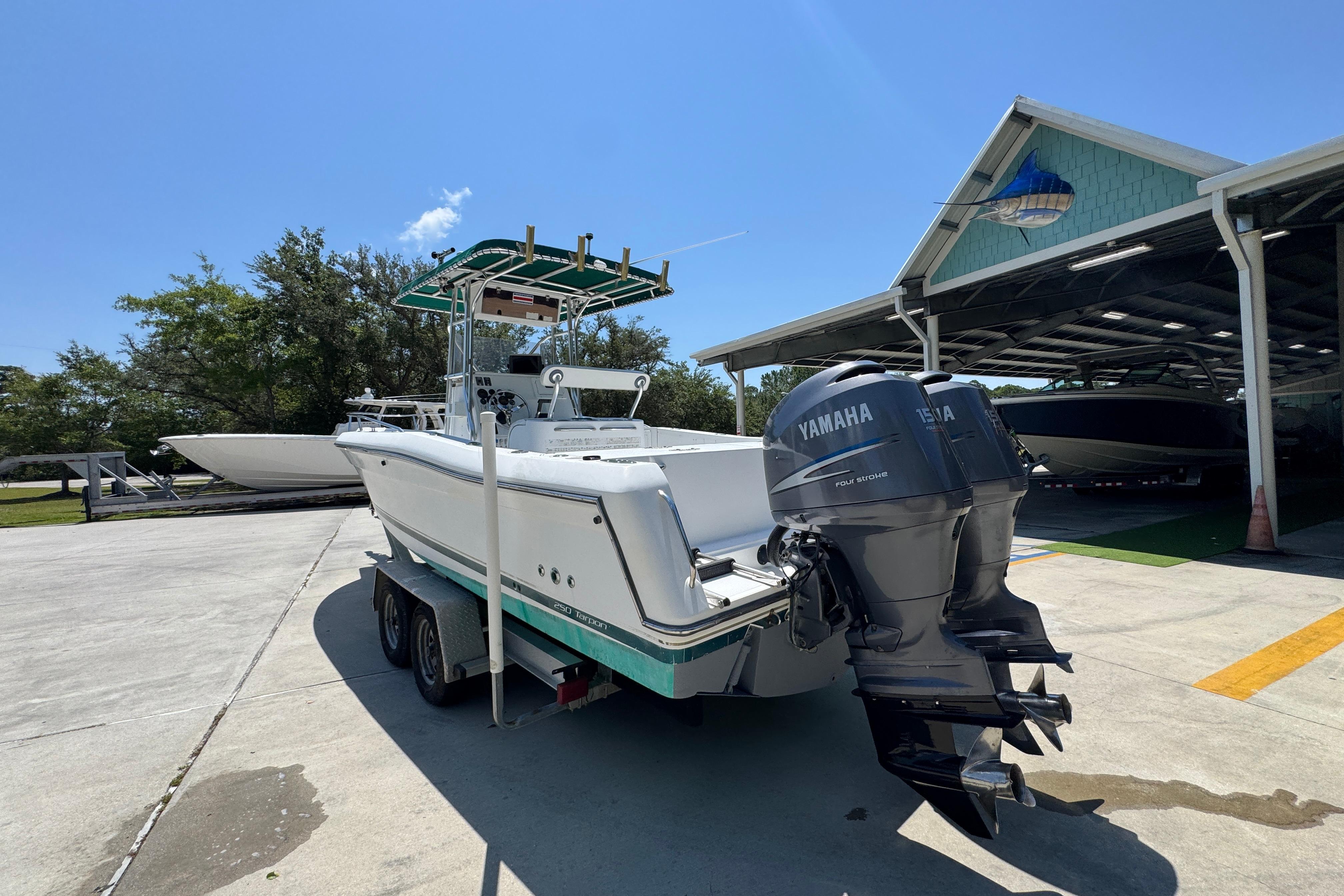 2000 Stamas 250 Tarpon boat with Yamaha engines on a trailer, parked outdoors.