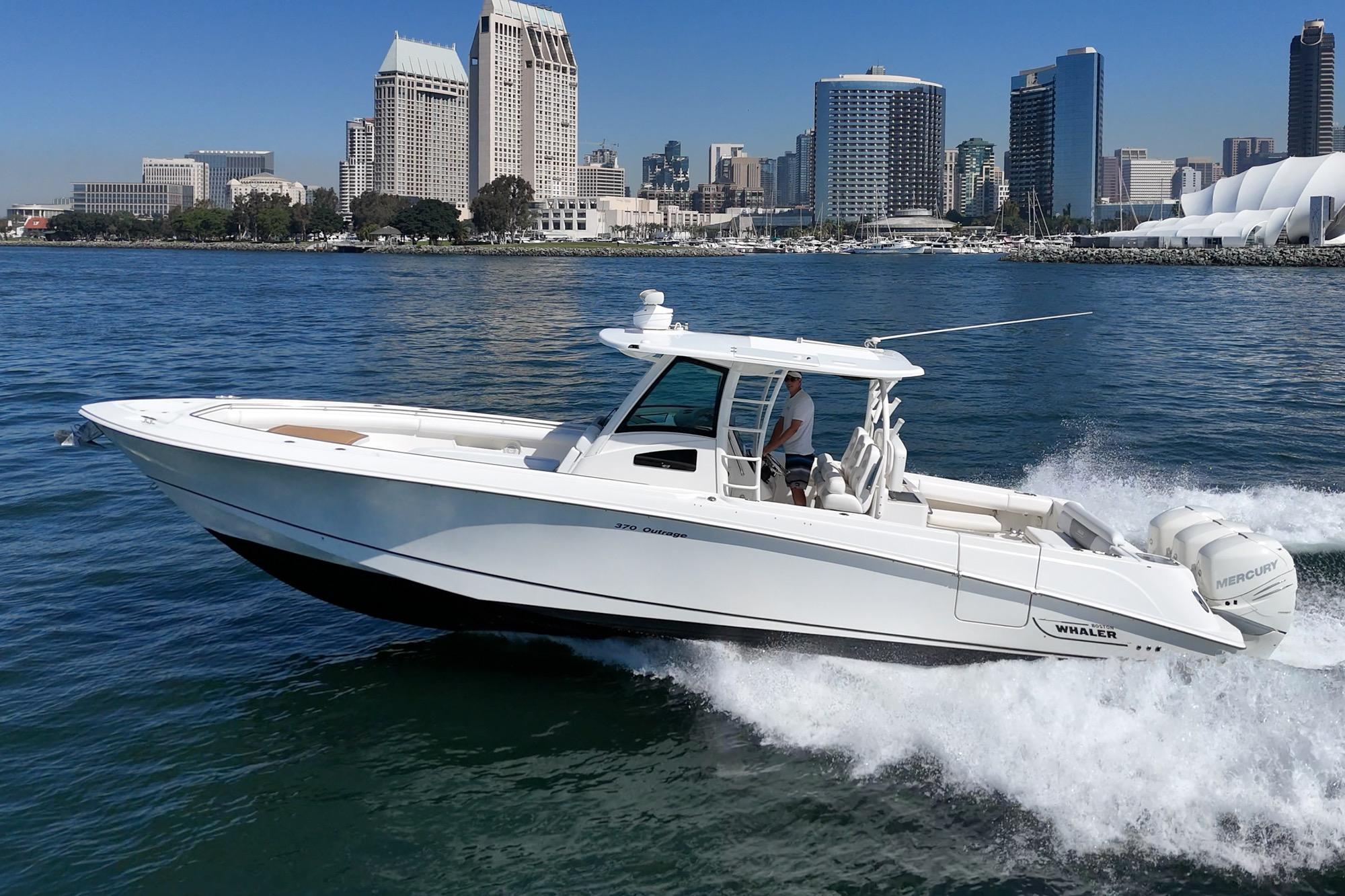 2015 Boston Whaler 370 Outrage cruising on water with city skyline backdrop.