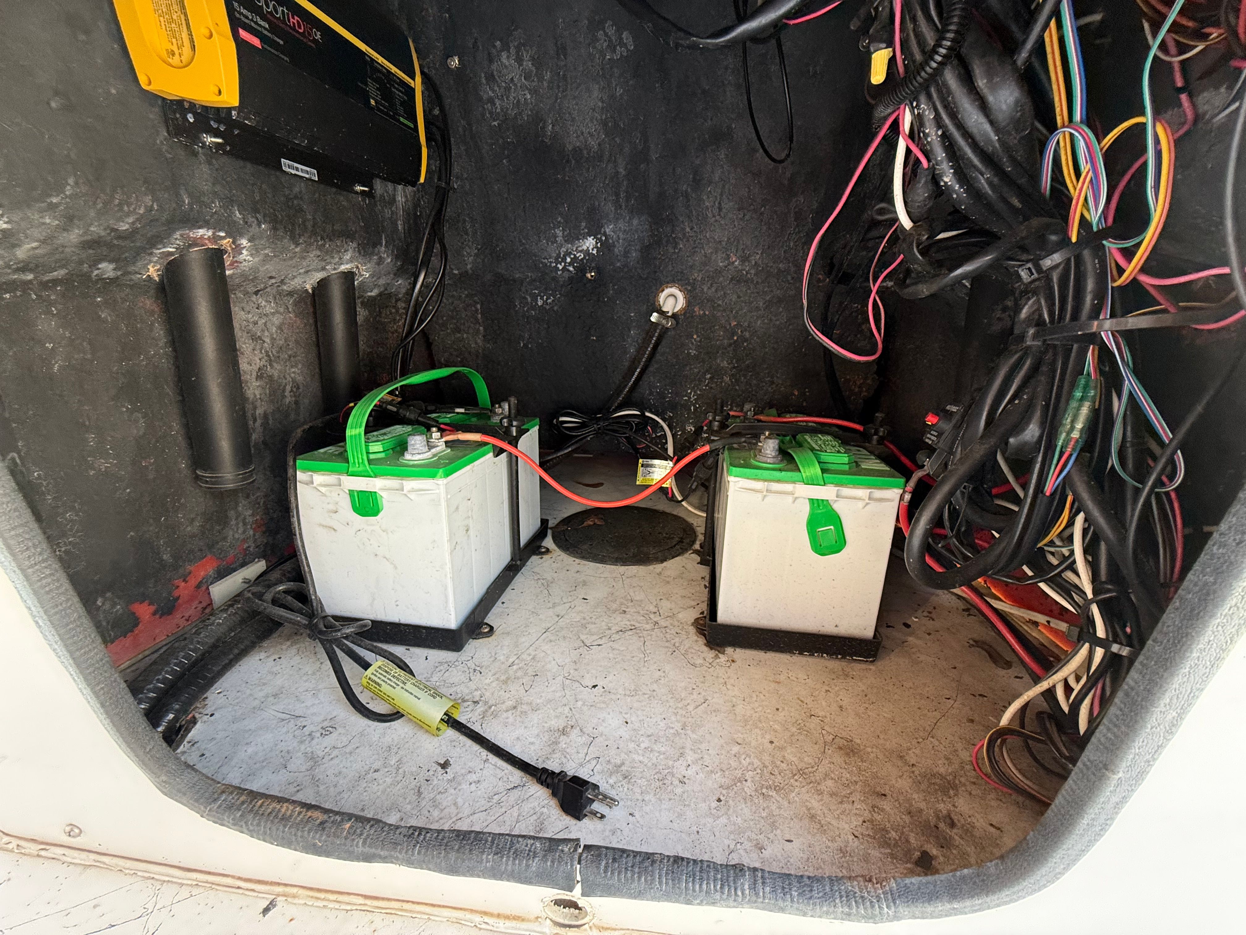 Two batteries in a boat's engine compartment with cables and connections.