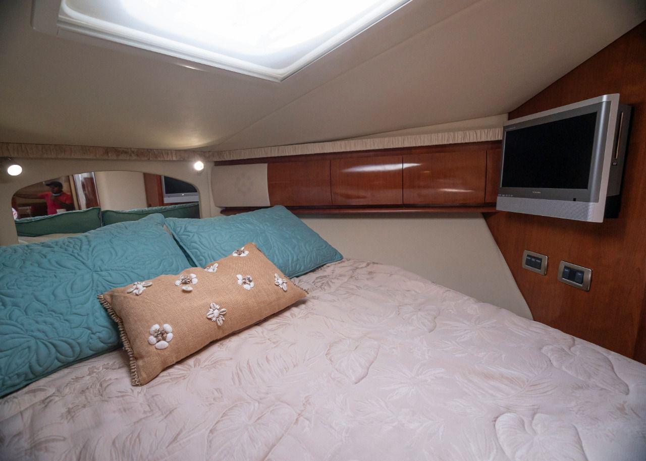 Interior cabin of 2006 Sea Ray 440 Sundancer with bed, pillows, and wall-mounted TV.
