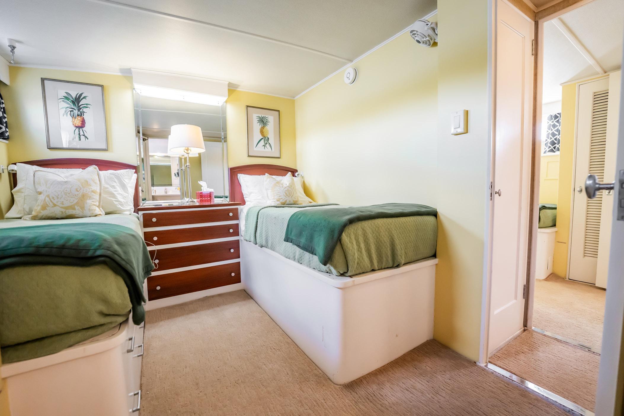 Twin bedroom in 1972 Trumpy 72 Motor Yacht with pineapple artwork and green bedding.