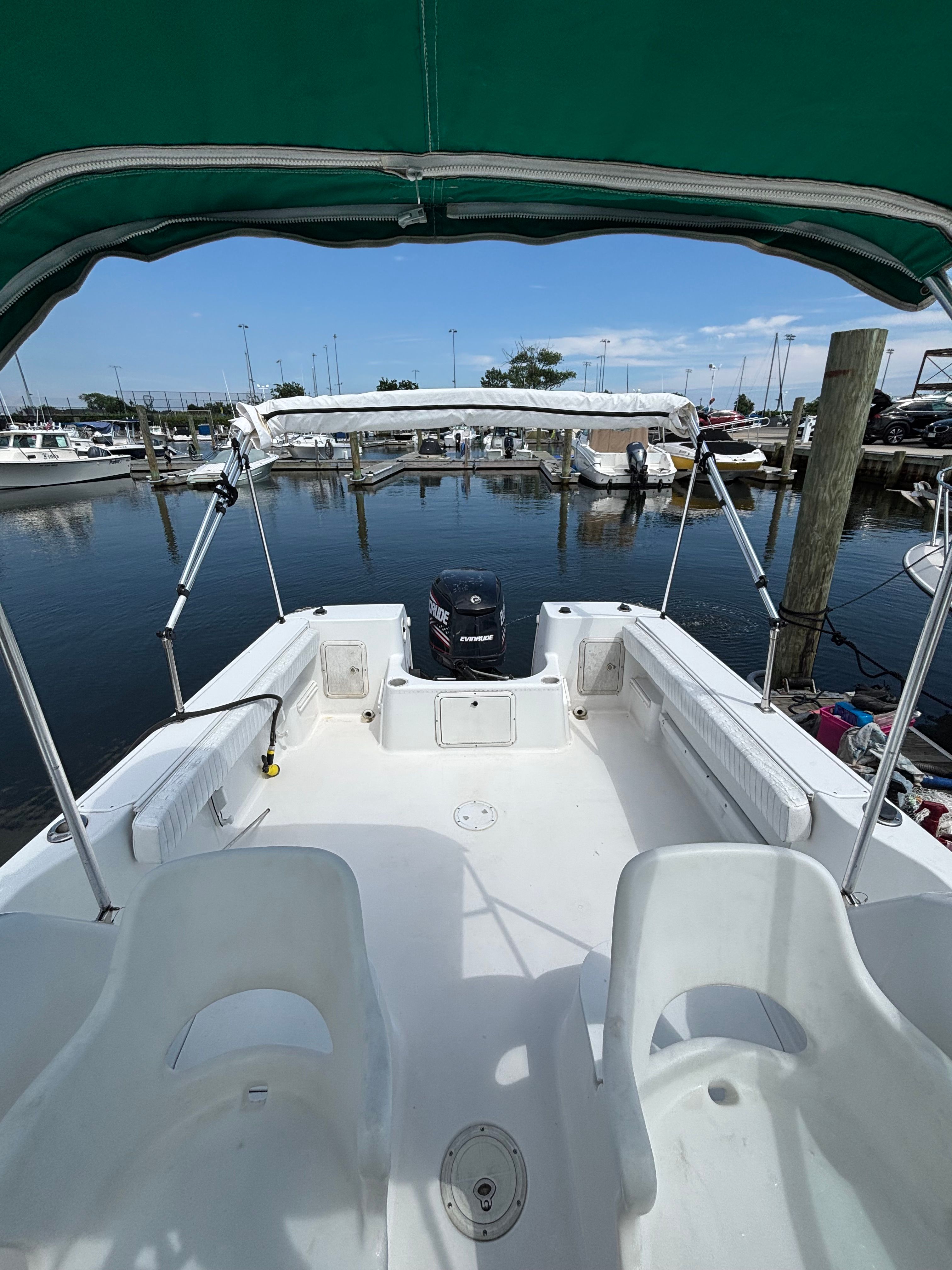 The image shows the cockpit of a 1999 Pro-Line 221 Walk Around boat in a marina.