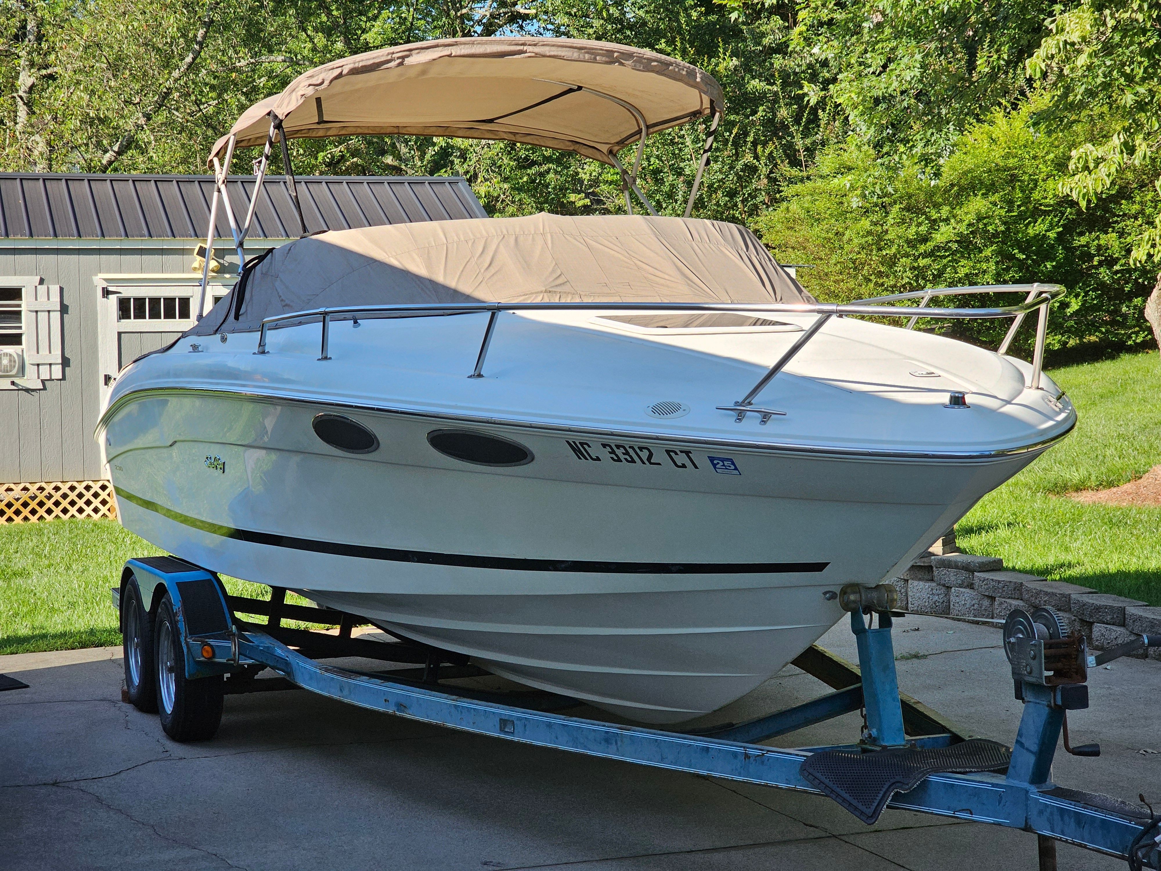 A 1997 Sea Ray 230 Overnighter Signature on a trailer in a garden.