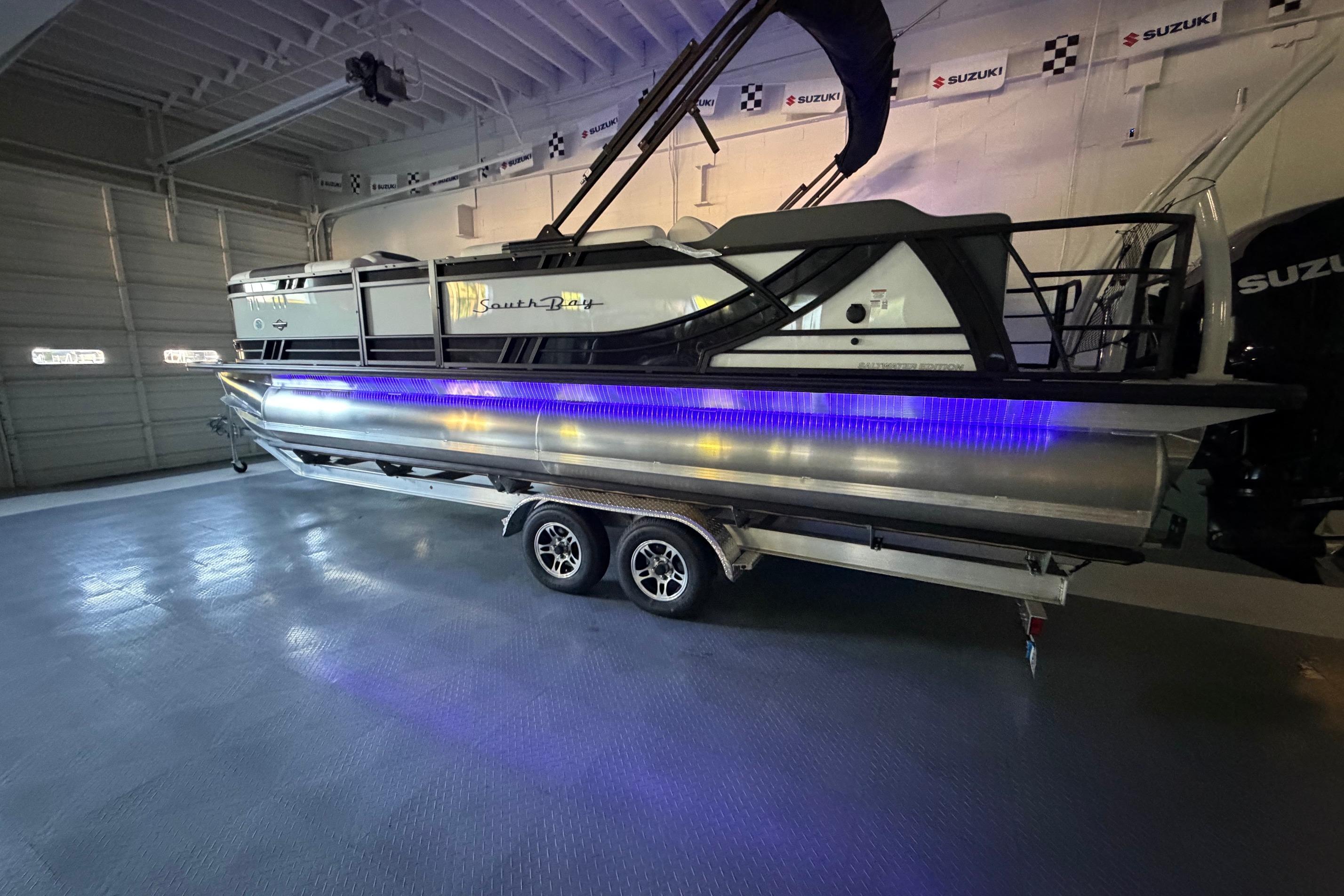 2026 South Bay 525SB2 pontoon boat with blue LED lights in a showroom.