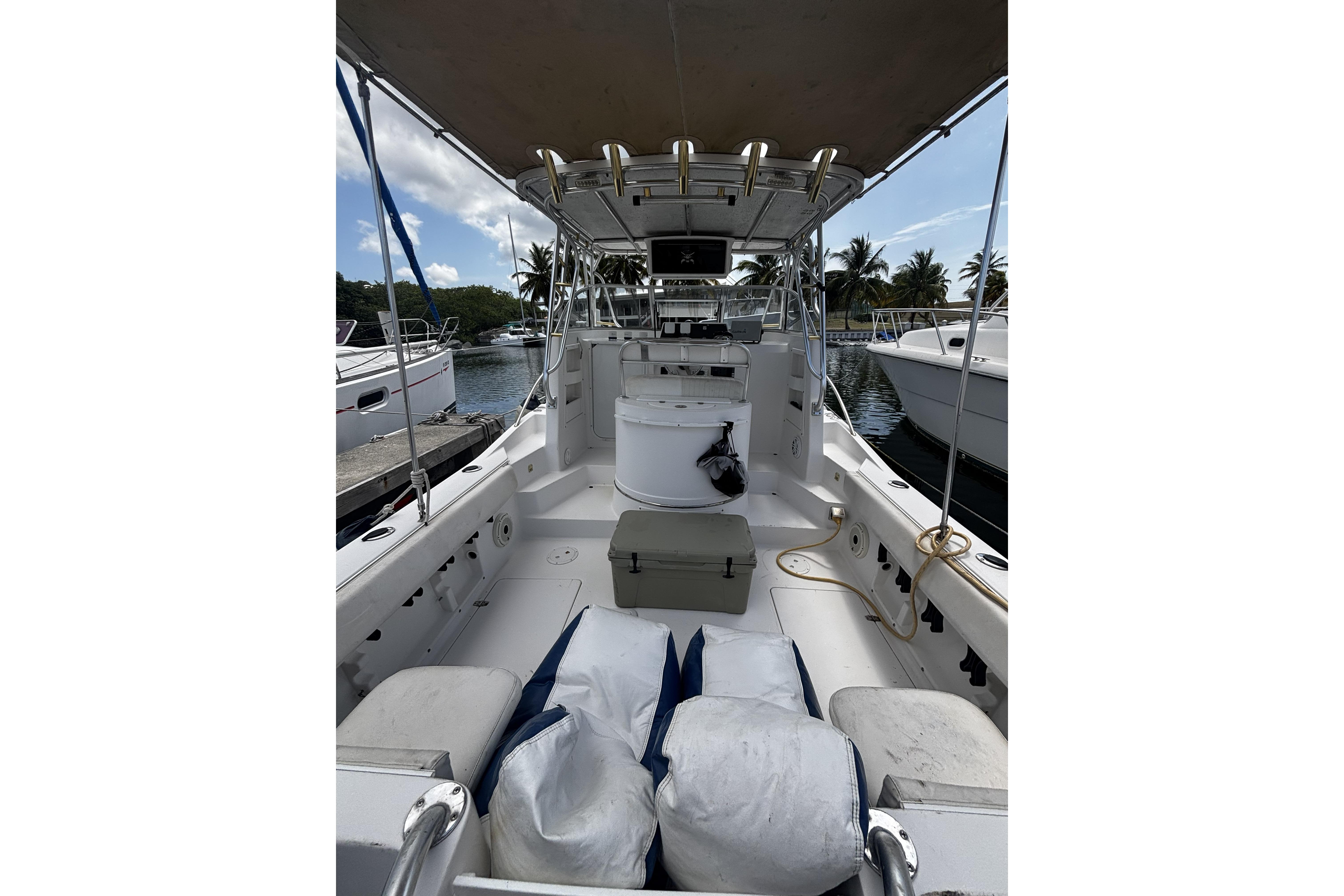 2005 Prosports 2860 KATWA boat interior with seating, storage, and canopy in marina setting.