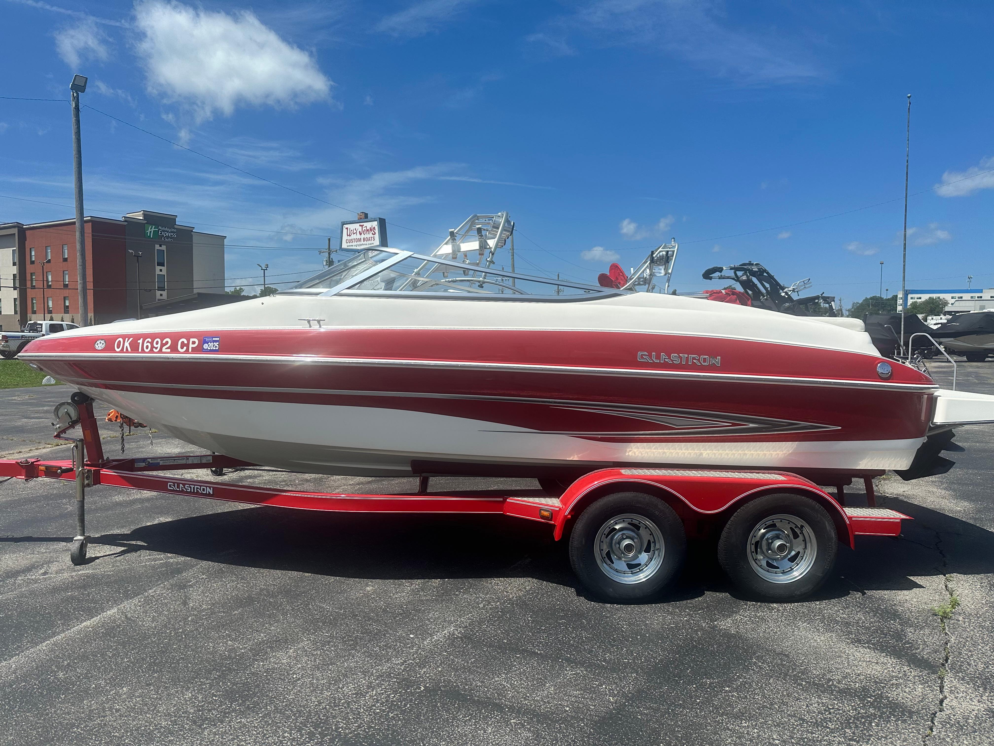 2008 Glastron 205 GX boat on trailer, red and white design, parked outdoors.