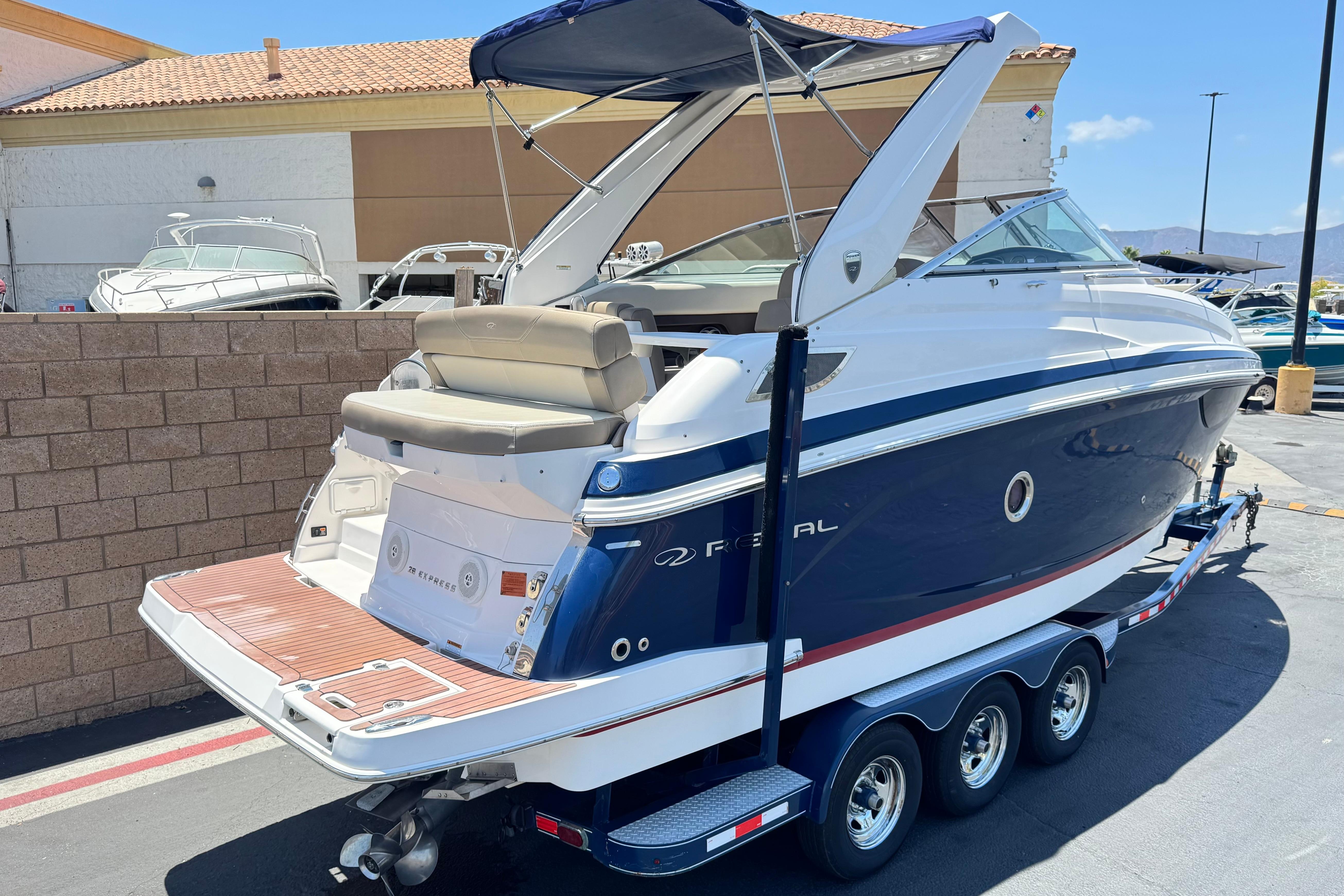 2013 Regal 28 Express boat on trailer, blue and white, parked outdoors.