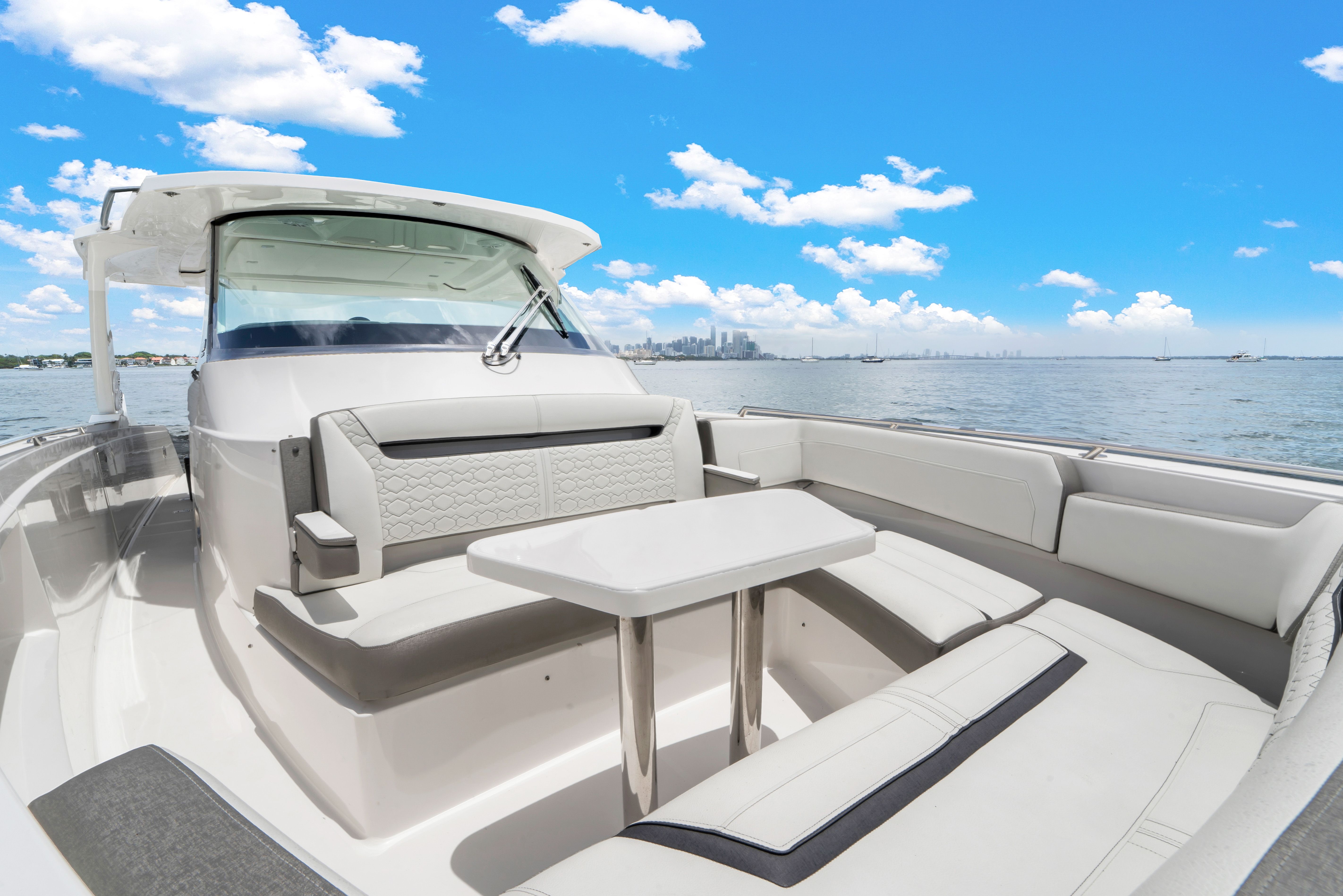 2023 Tiara Yachts 38 LS with stylish seating area and table, on calm water under a blue sky.