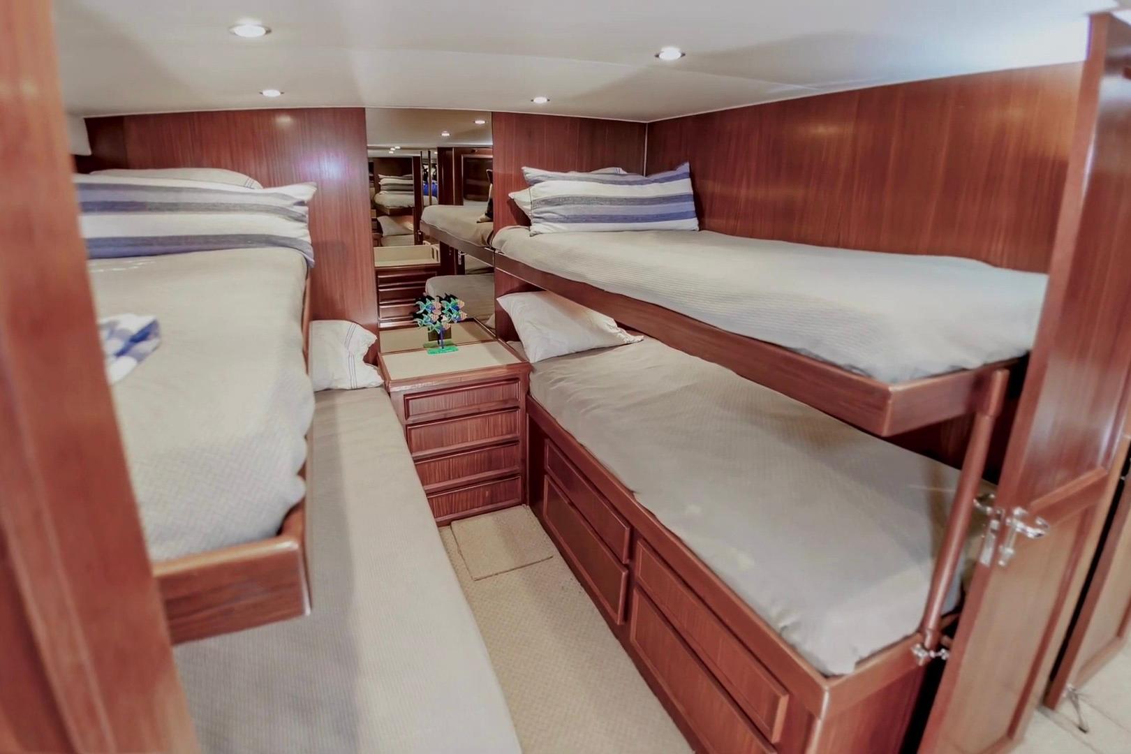 Cozy cabin with bunk beds in 1980 Hatteras 70 Motor Yacht, featuring wood paneling.