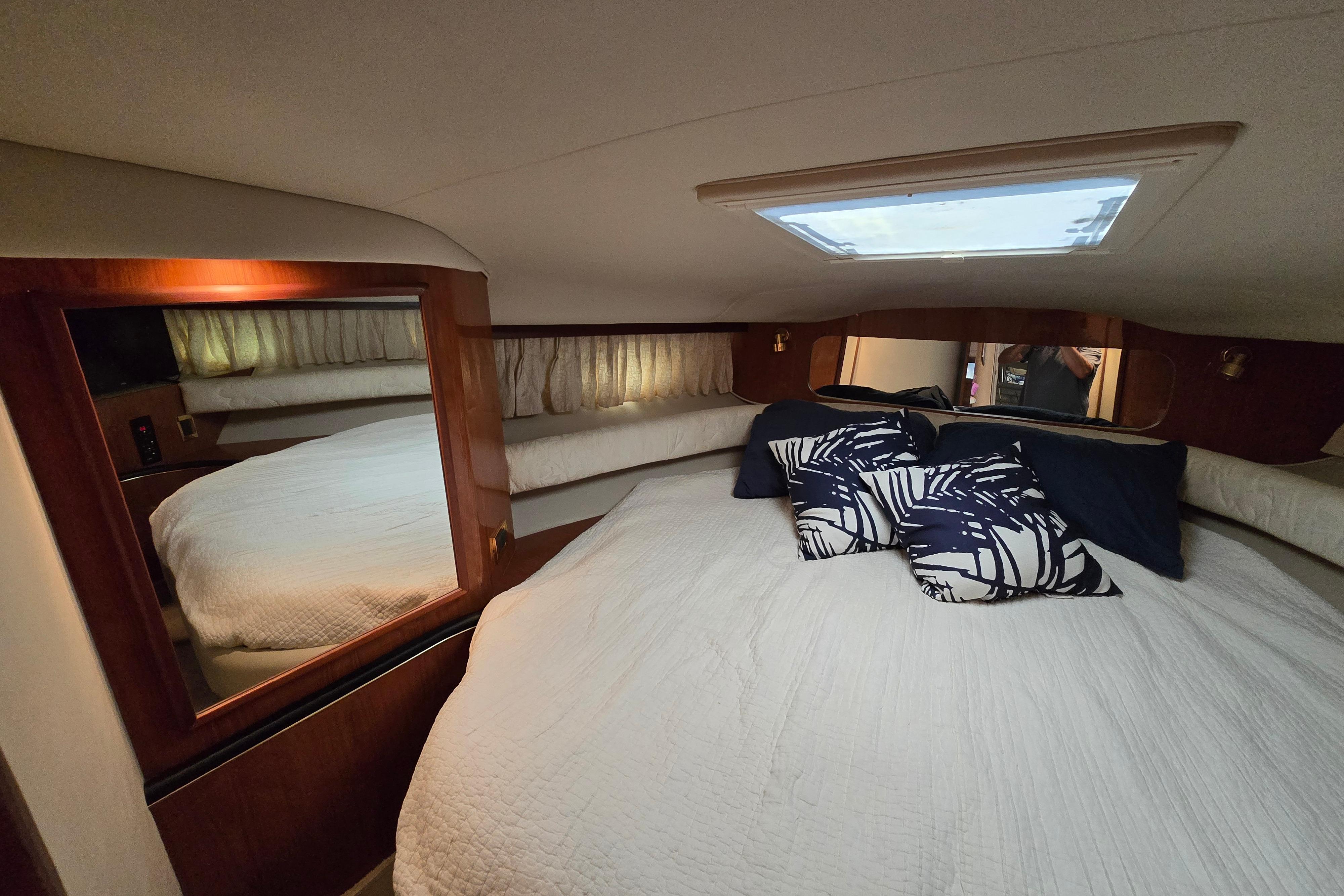 Interior cabin of 1999 Sea Ray Sundancer 400 with cozy bedding and decorative pillows.