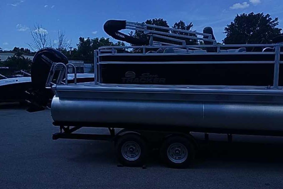 2026 Sun Tracker SportFish 22 DLX pontoon boat on trailer, parked outdoors.