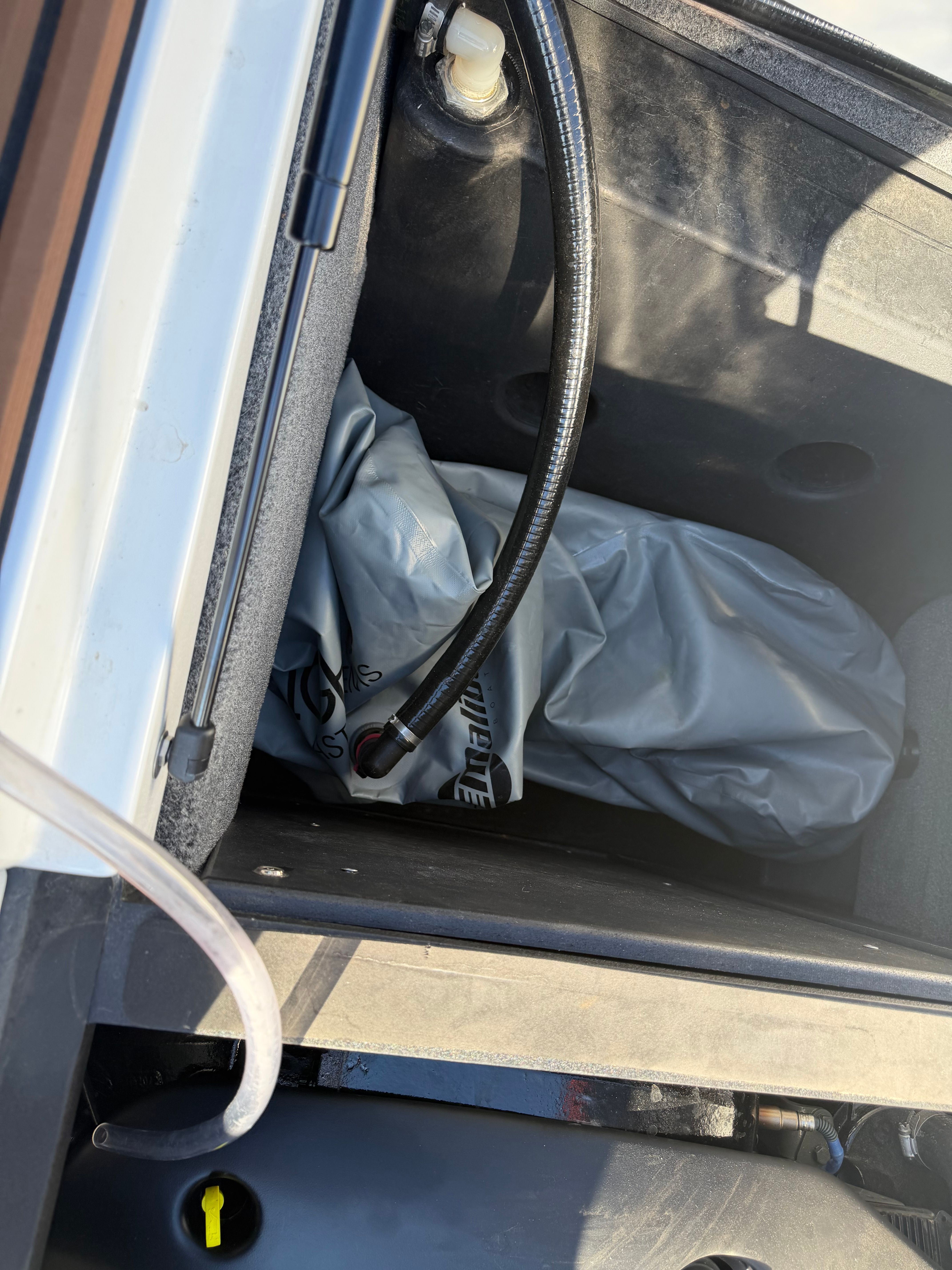 A view inside the storage compartment of a 2021 Malibu Wakesetter 23 LSV with a hose and cover.