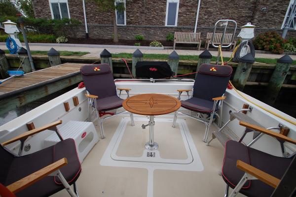 The image shows the aft deck of a 2005 Fox Island Thirty - Sedan Cruiser with four chairs around a round table.