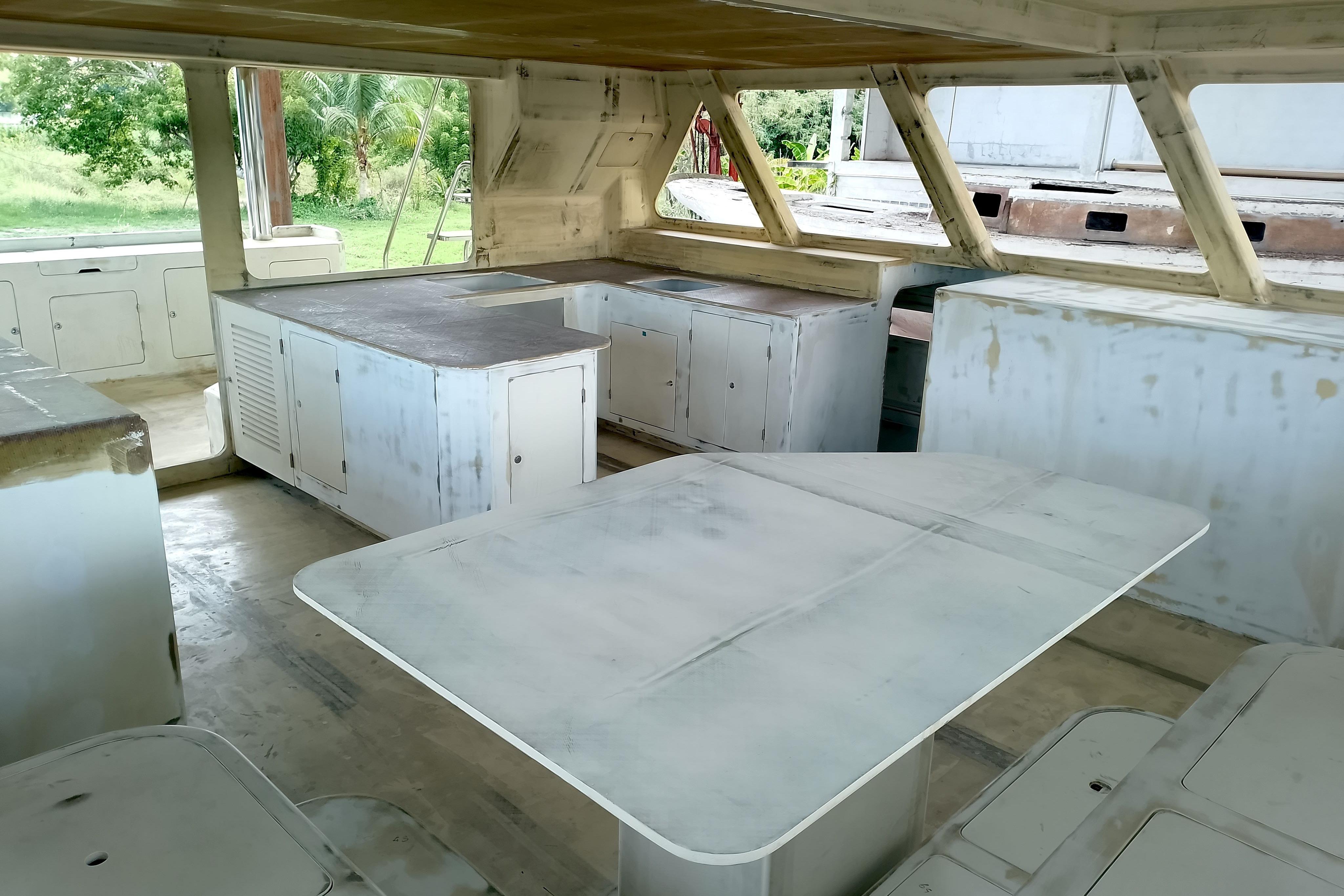 Interior of 2026 Schionning Prowler 1500 catamaran under construction, featuring unfinished cabinetry and seating.