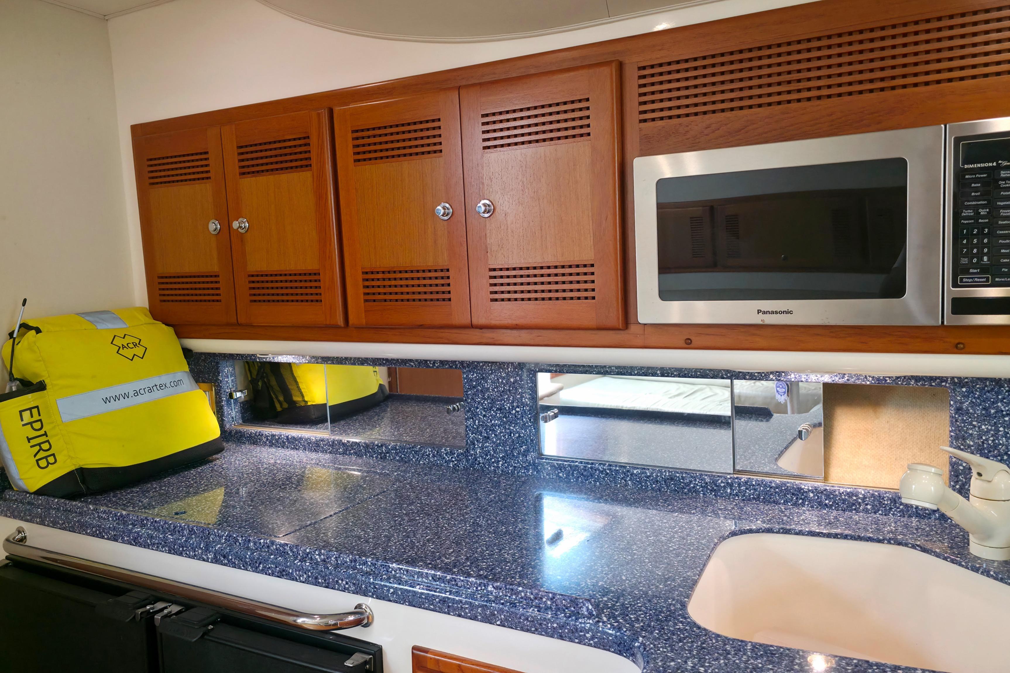 2004 Cabo 40 Hardtop Express galley with wooden cabinets, microwave, and EPIRB safety equipment.
