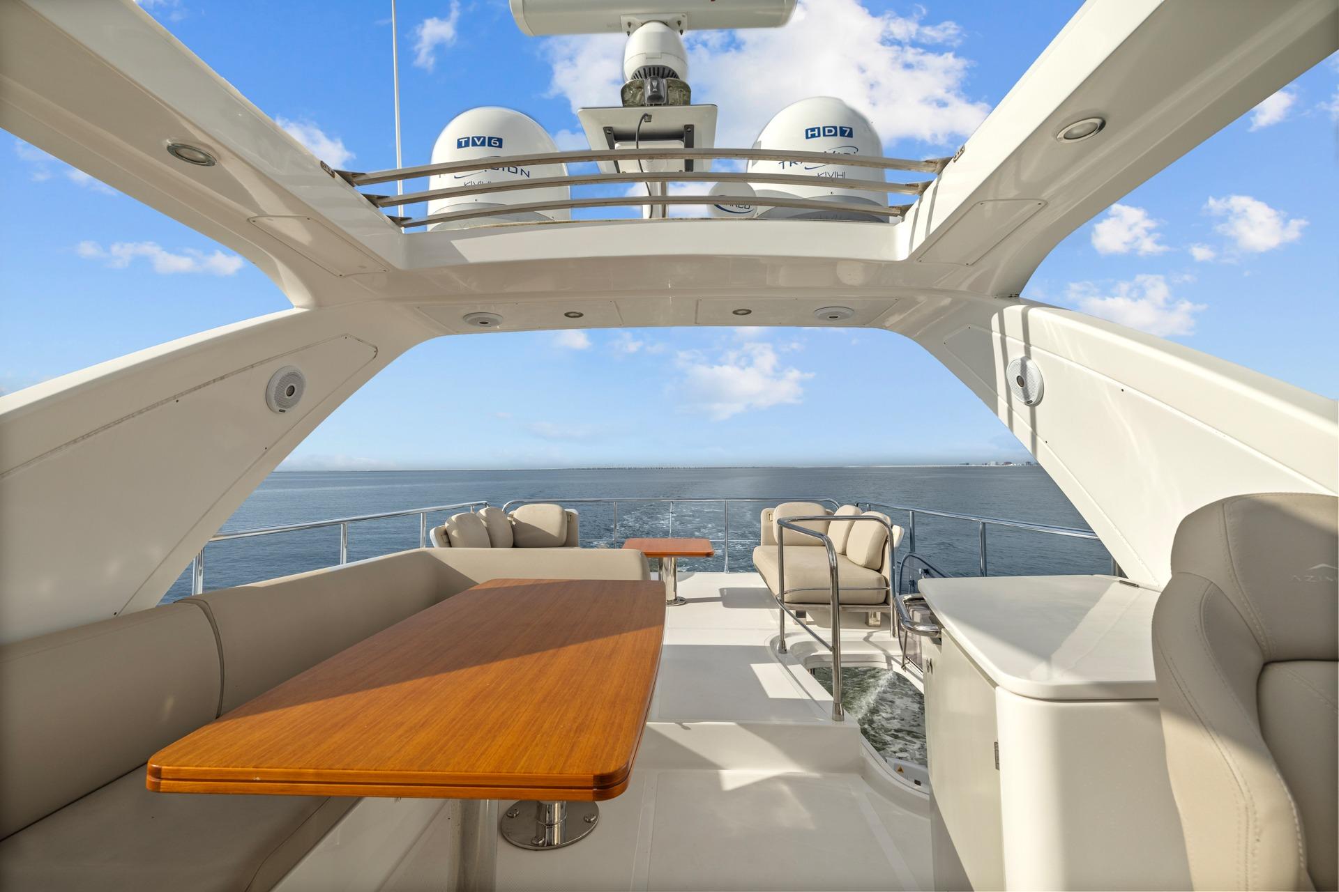 Luxurious 2019 Azimut 55 yacht deck with seating, table, and ocean view.