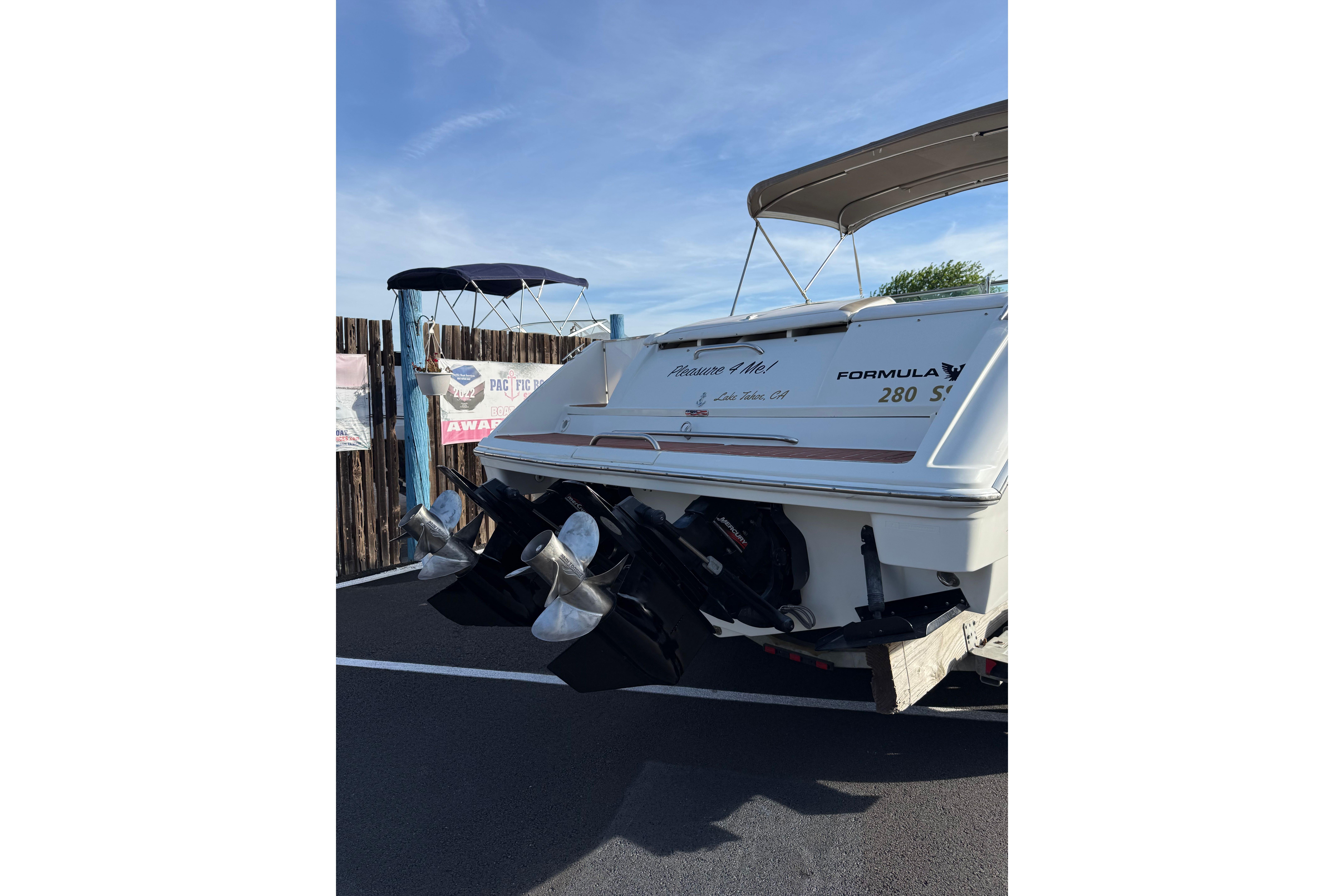 1999 Formula 280 Sun Sport boat with dual propellers, parked outdoors.