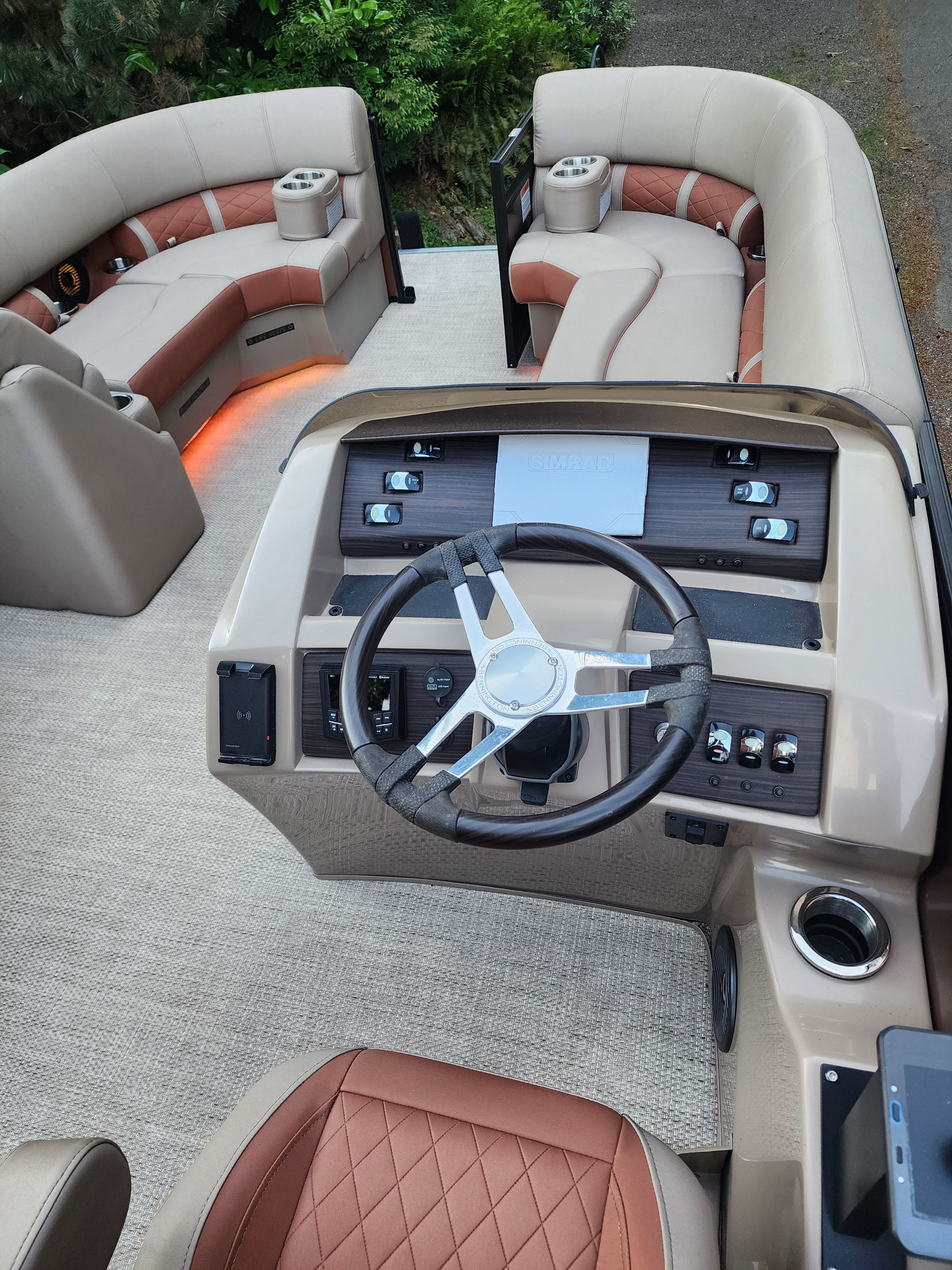 The image shows the cockpit of a Bennington 22 LSB pontoon boat with luxurious seating and a modern helm.