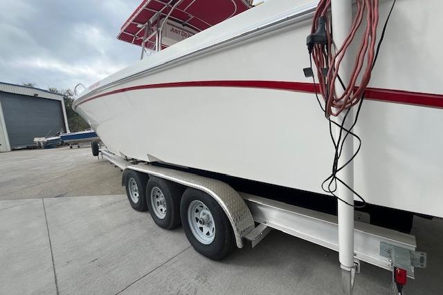 2001 Fountain 38 Center Console boat on trailer, side view with red stripe.