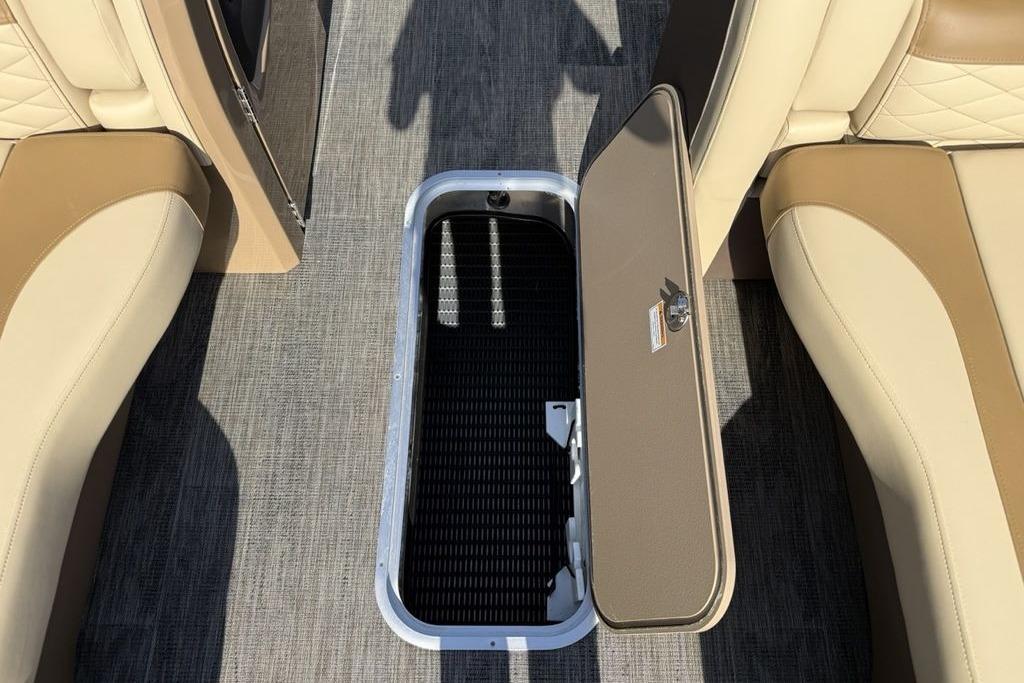 2026 Godfrey Monaco 235 SB boat interior with open storage compartment and beige seating.